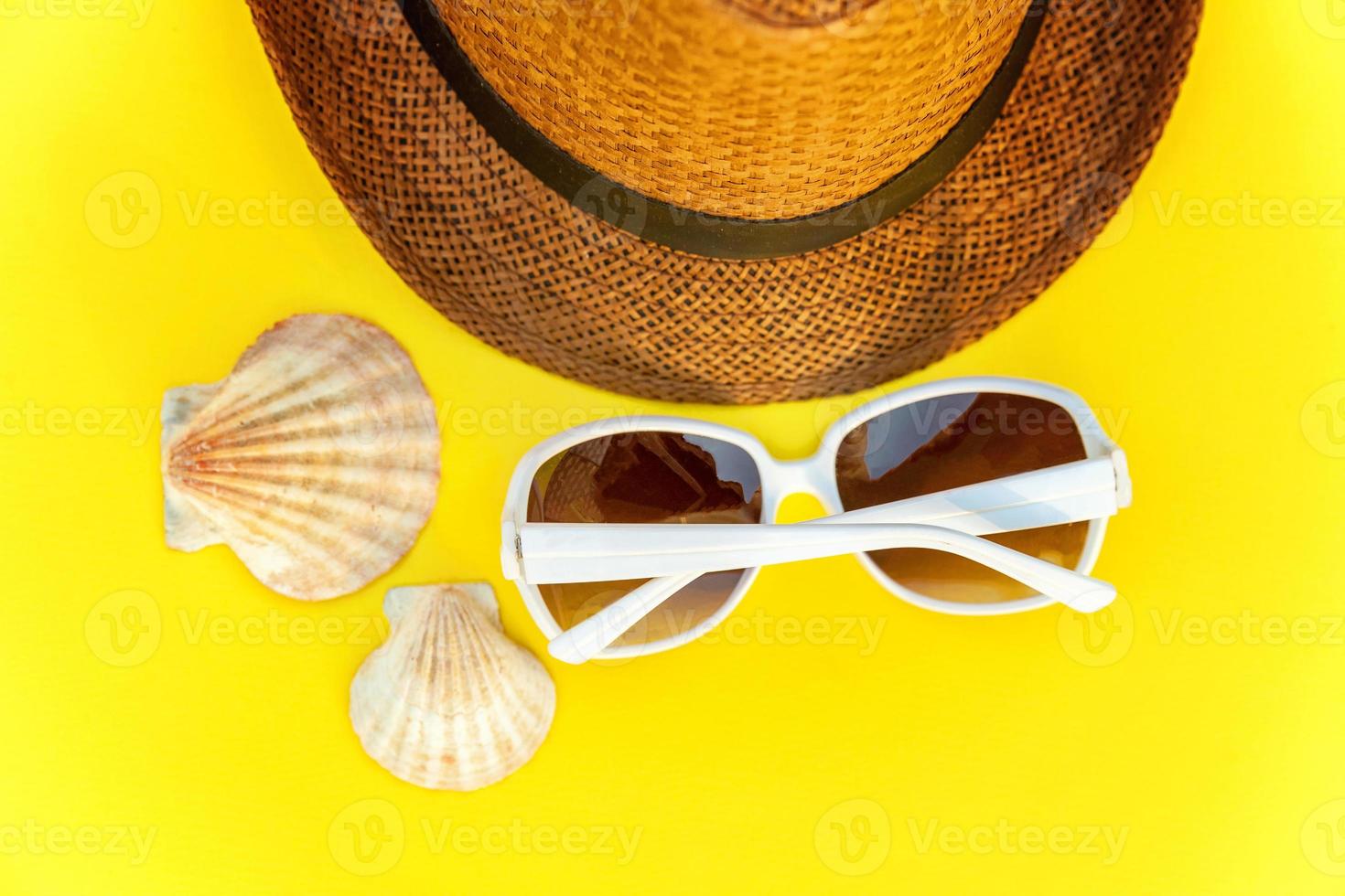 Sunglasses, shell and retro hat on yellow background photo