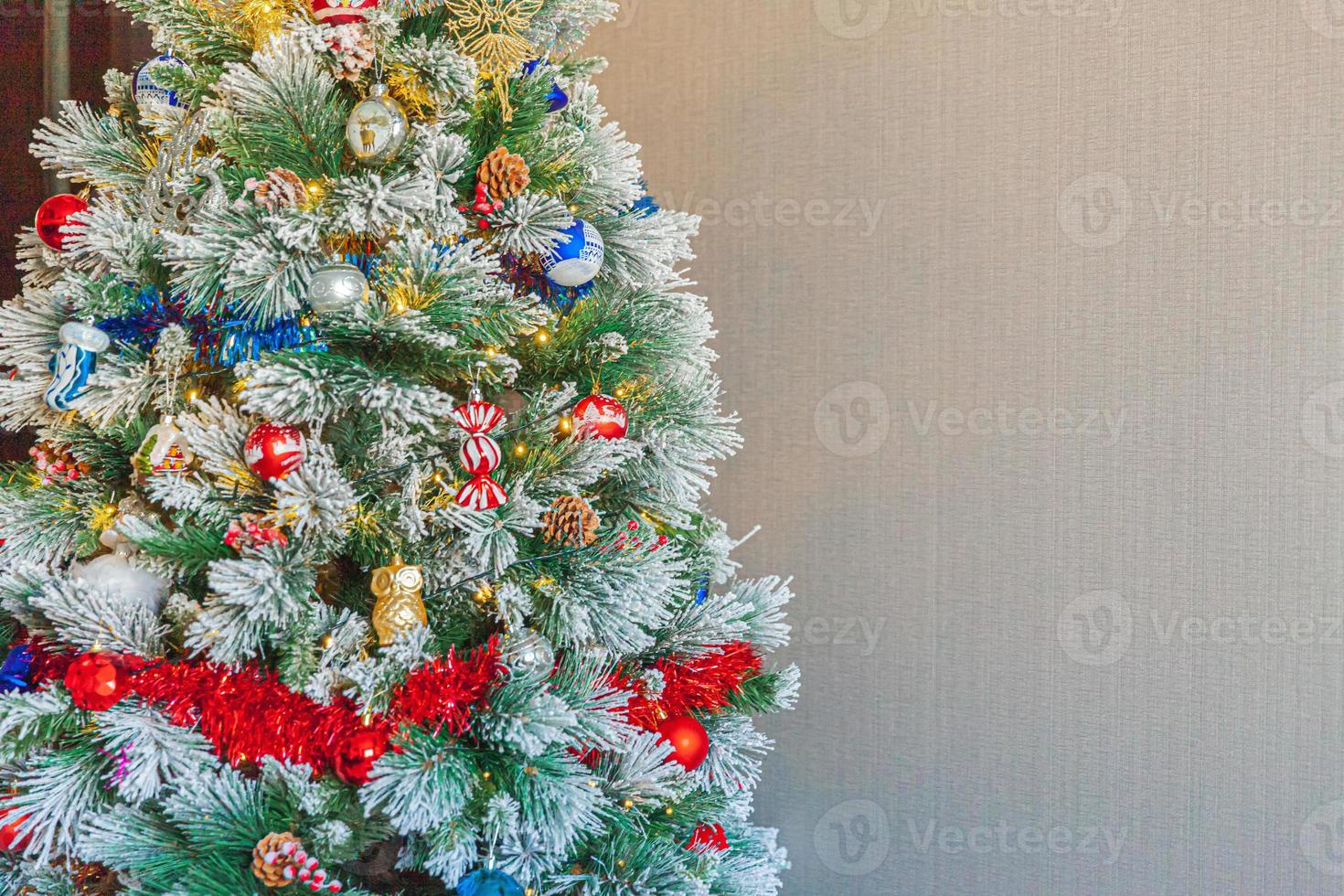 Classic Christmas decorated New year tree with red blue and white ornament toy and ball on gray wall background. Modern classical style interior design apartment. Christmas eve at home. Copy space. photo