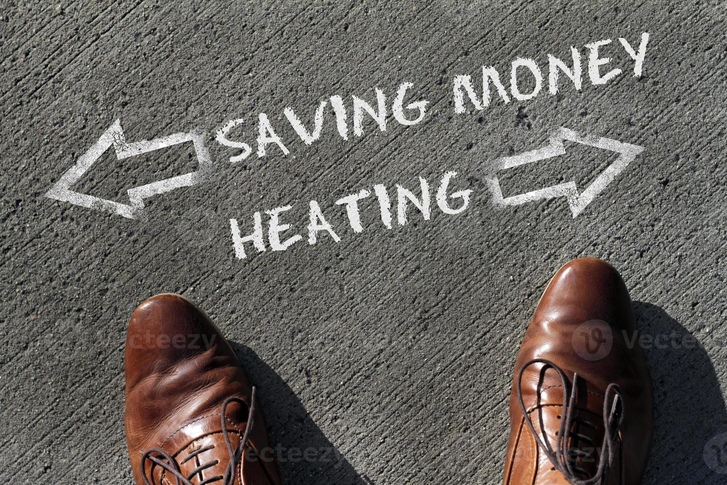 Person having to decide between Heating and Saving Money - top view of the words and arrows pointing in opposite directions photo