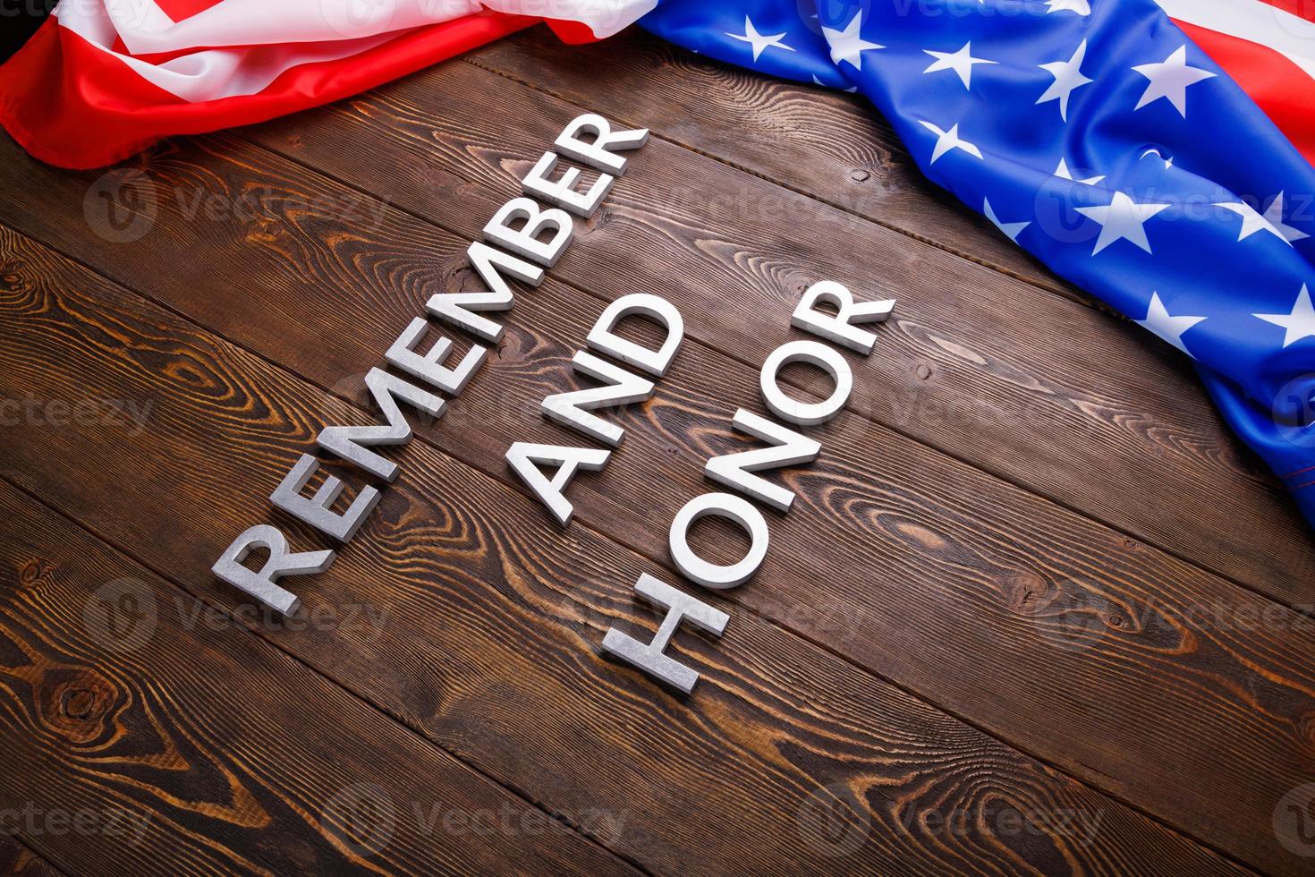 words remember and honor laid with silver metal letters on wooden background with USA flag on the right side photo