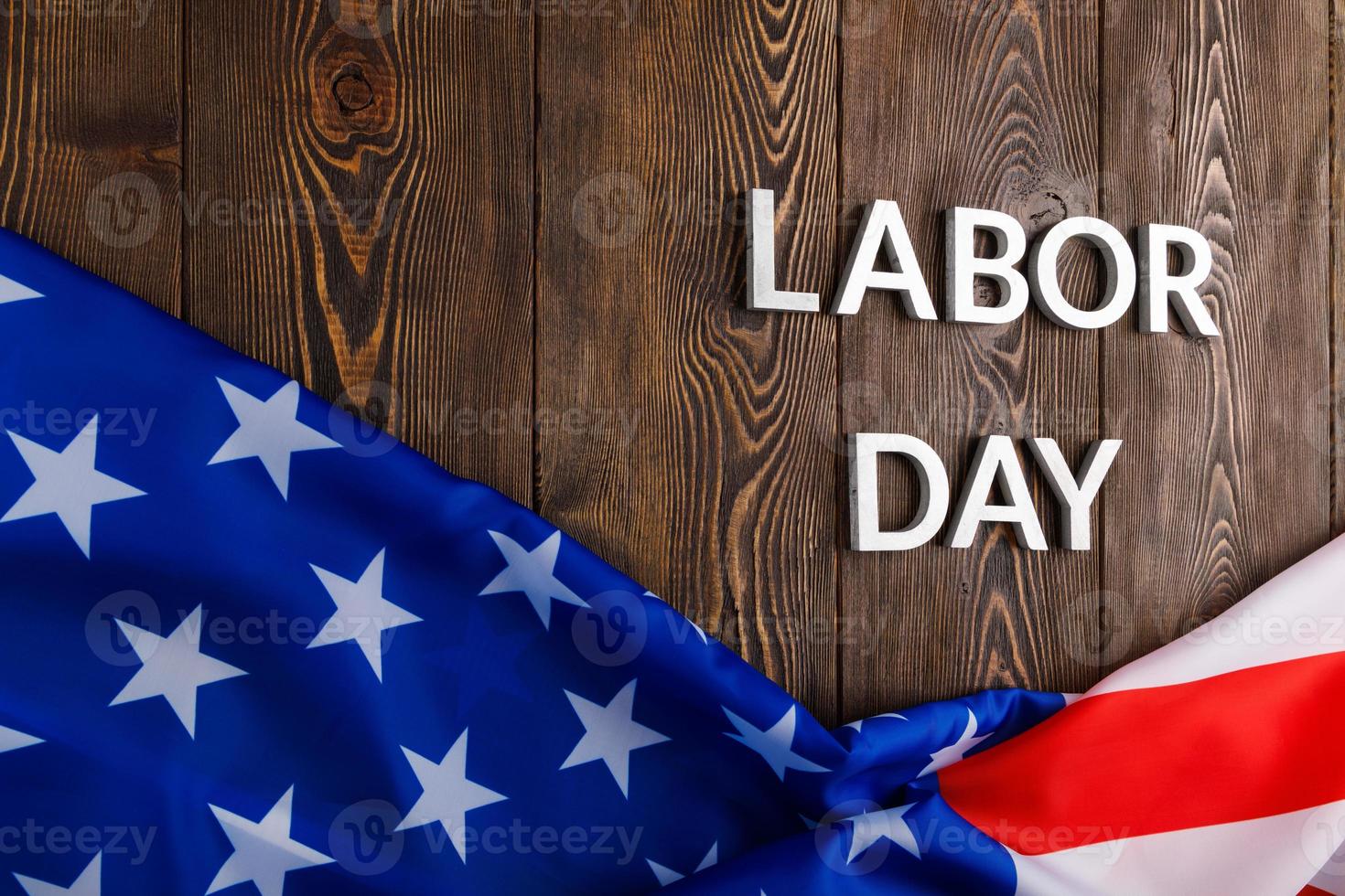 words labor day laid with silver metal letters on wooden surface with crumpled USA flag on bottom side photo