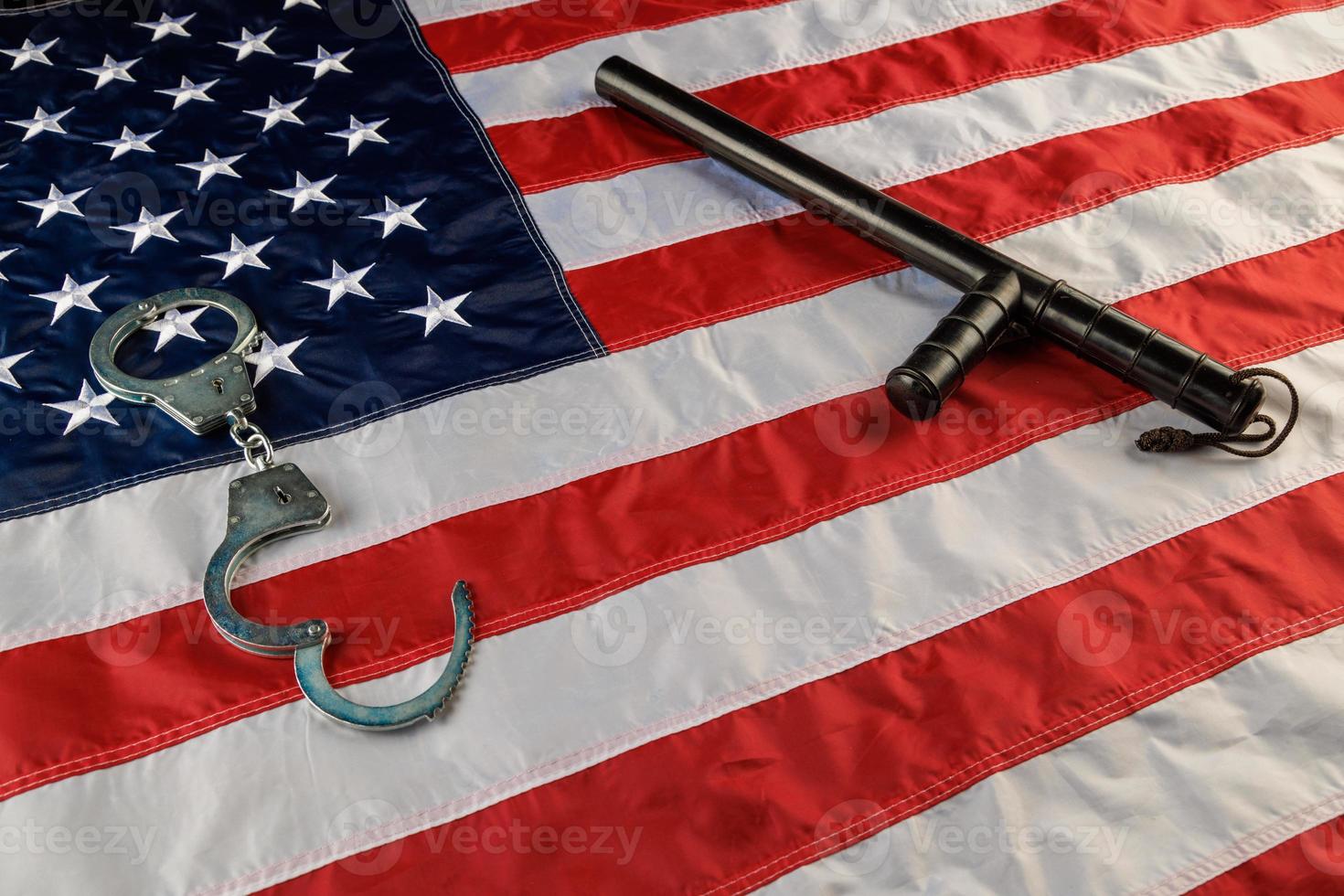 silver metal handcuffs and police nightstick over US flag on flat surface photo