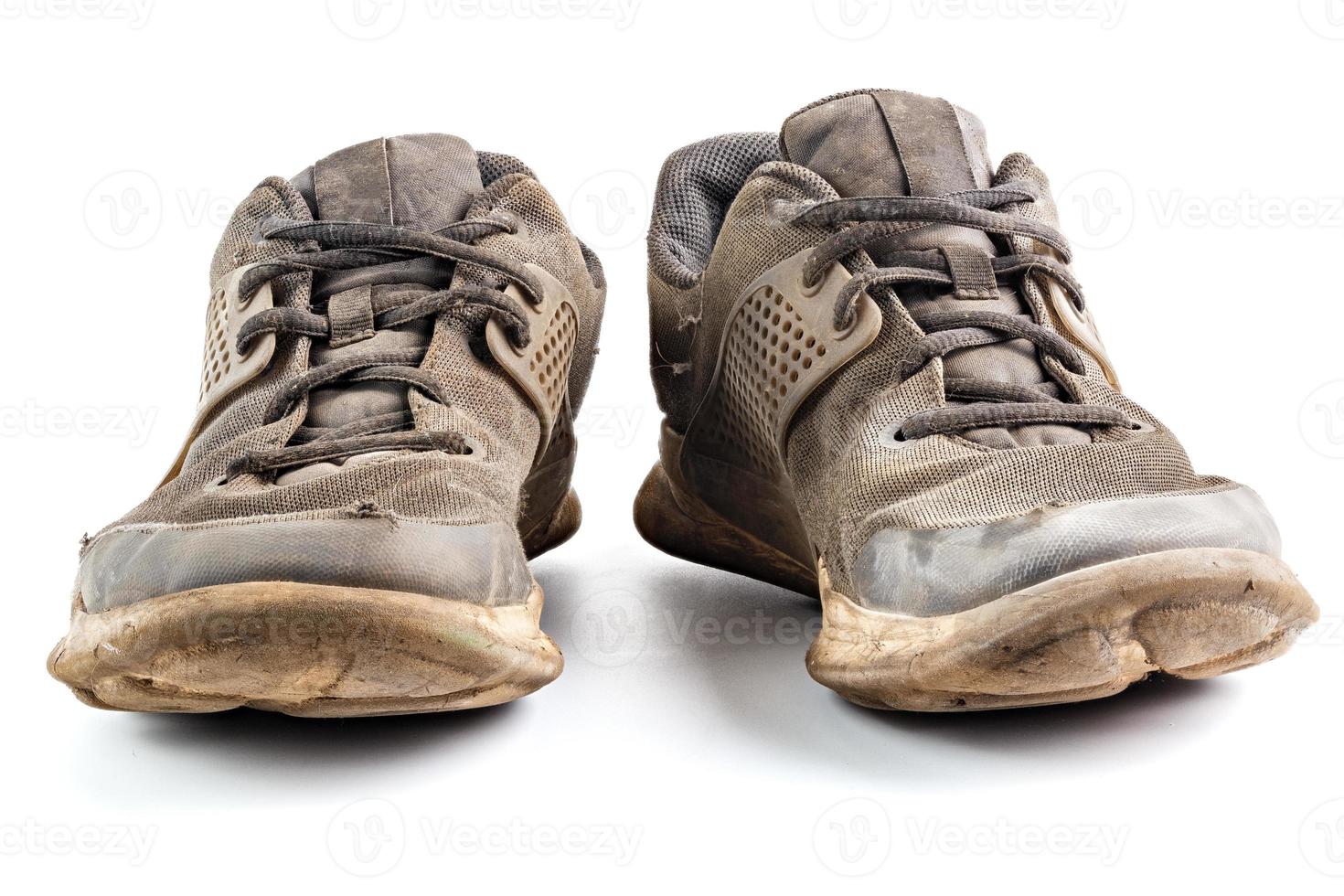a pair of weared dirty sneakers isolated on white background, frontal vew photo