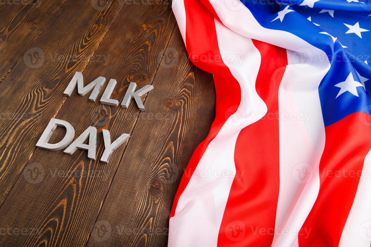 the word MLK day laid with silver metal letters on wooden surface with crumpled USA flag at upper side photo