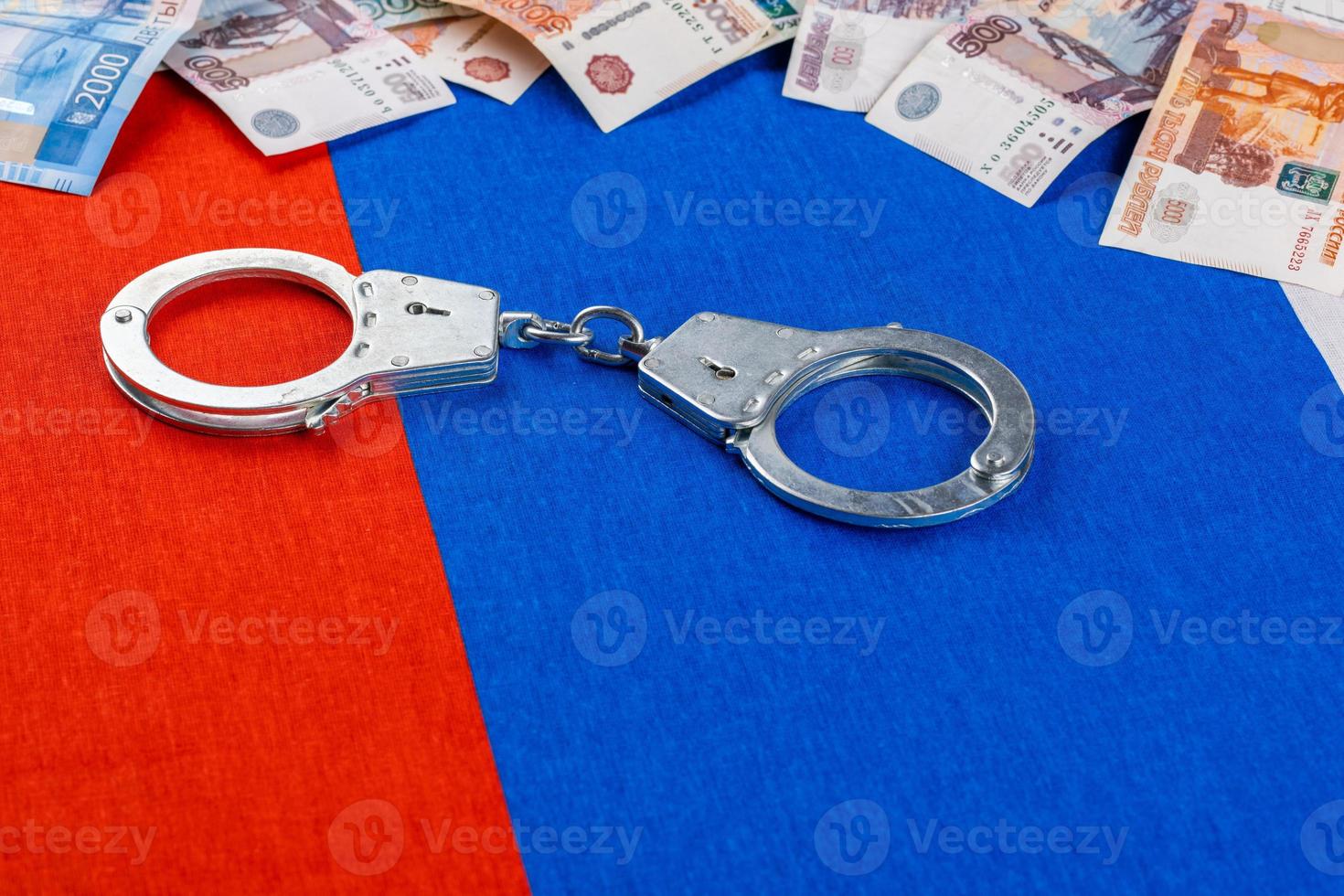 roll of us dollar banknotes and handcuffs on flat full-frame russian flag photo