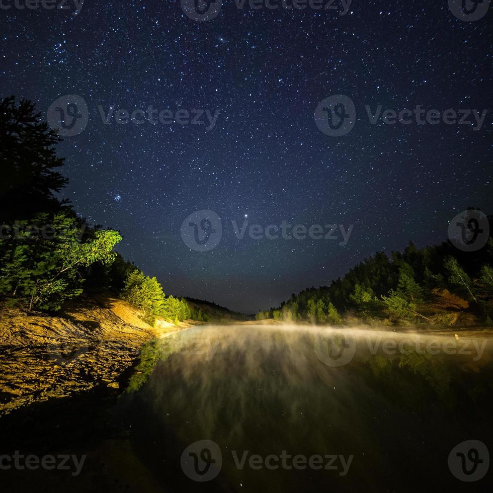 small lake under stars at night with foggy vapour at summer photo