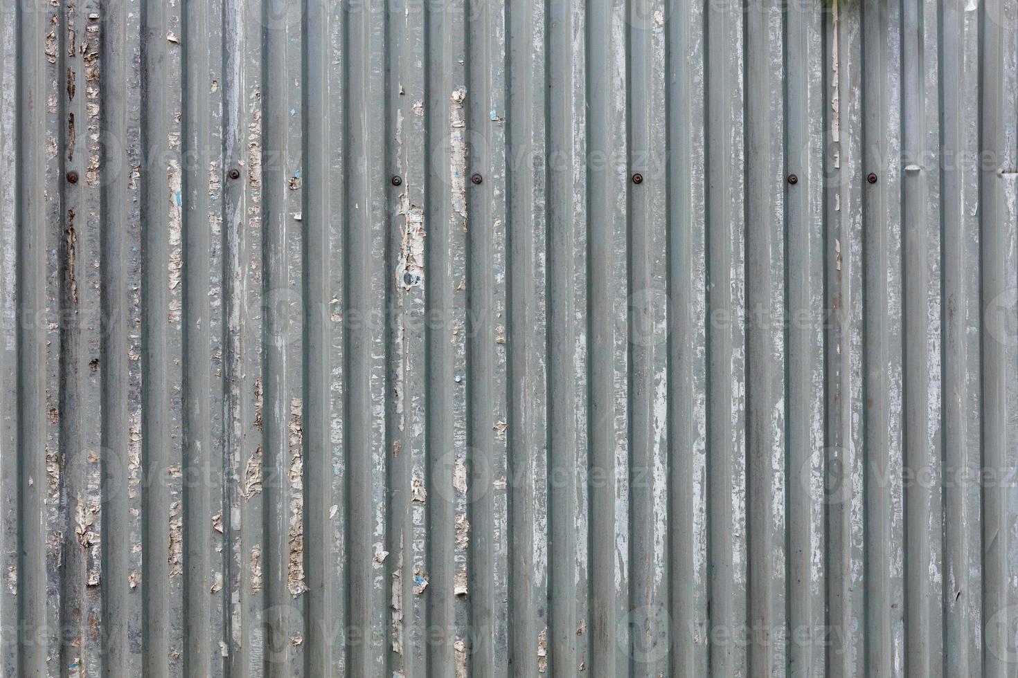 corrugated zinc-plated sheet fence with paper advertisements leftovers photo