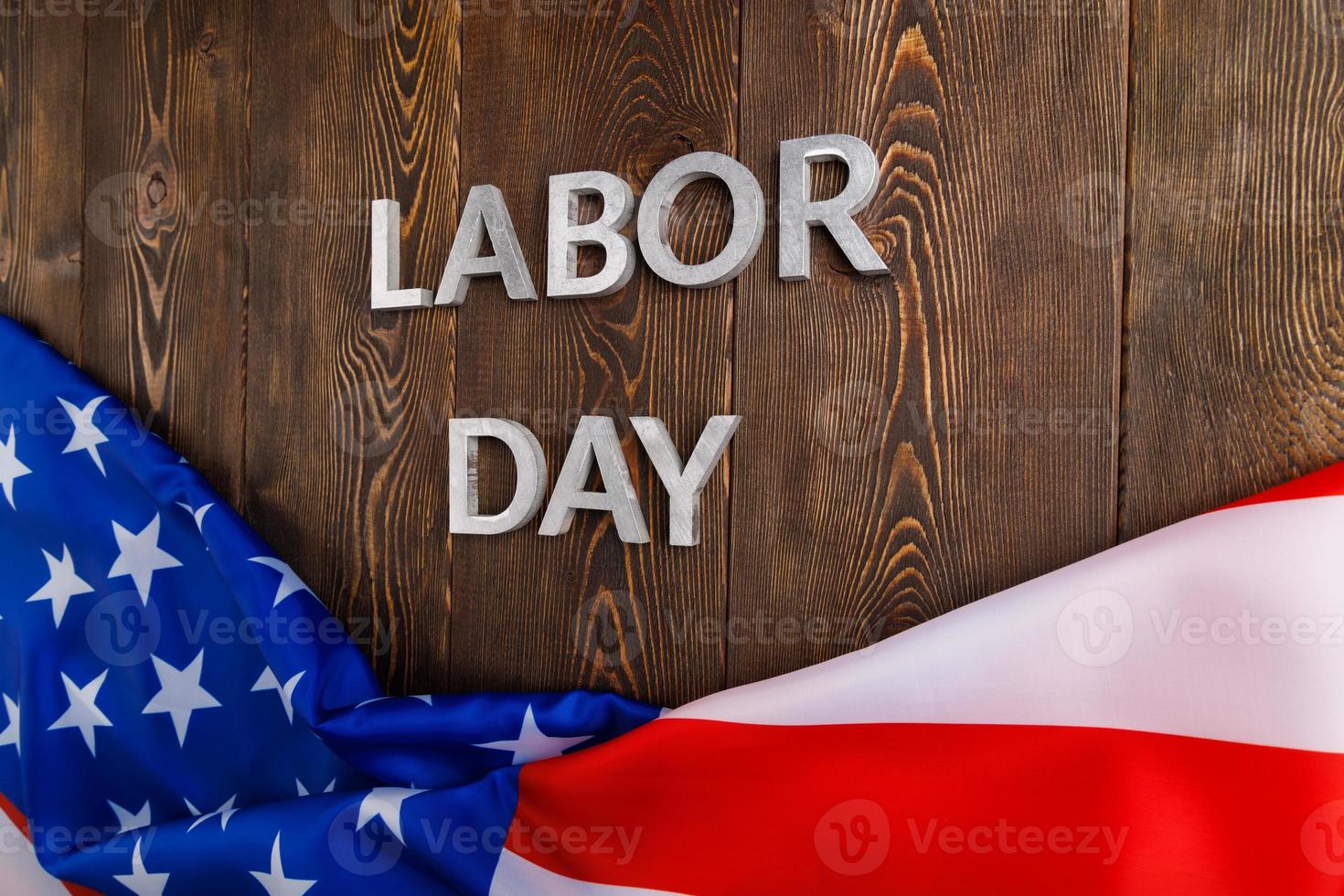 words labor day laid with silver metal letters on wooden surface with crumpled USA flag on bottom side photo