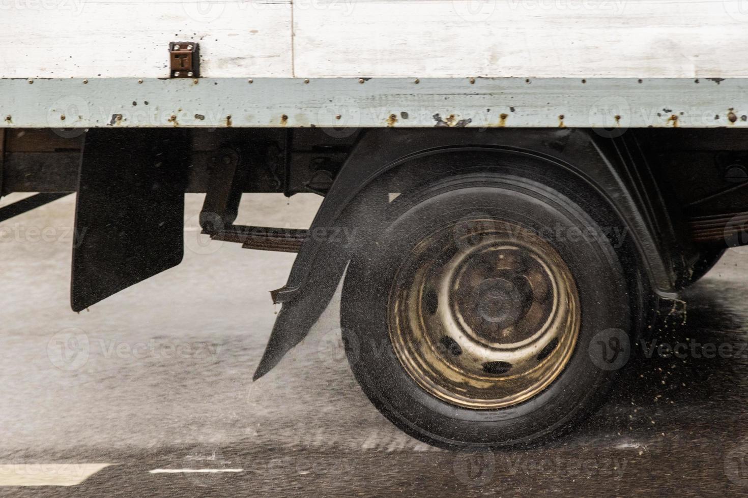 short box truck moving on a wet road with splashes during the day photo