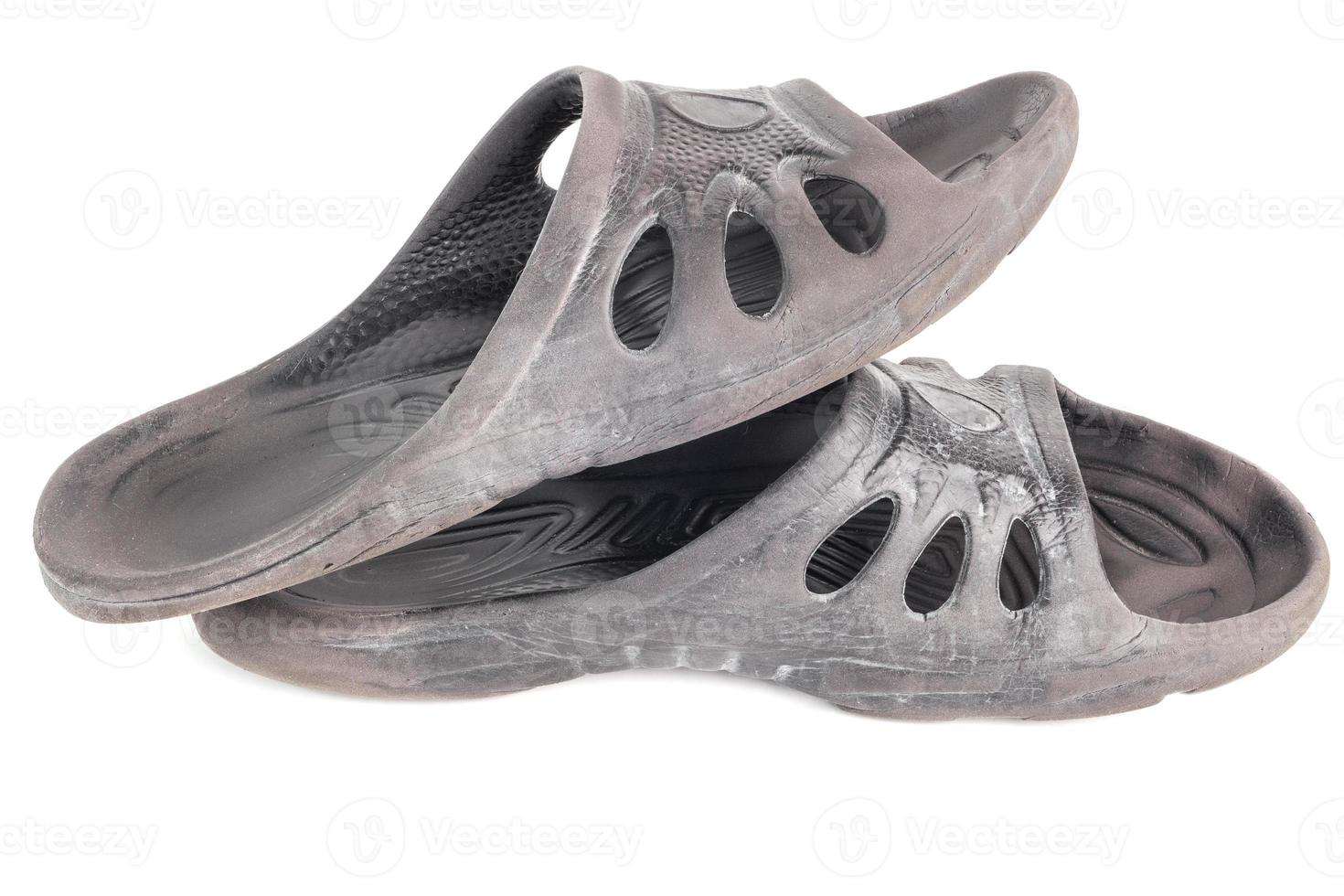pair of used cheap black soft rubber slippers with signs od friction wear isolated on white background photo