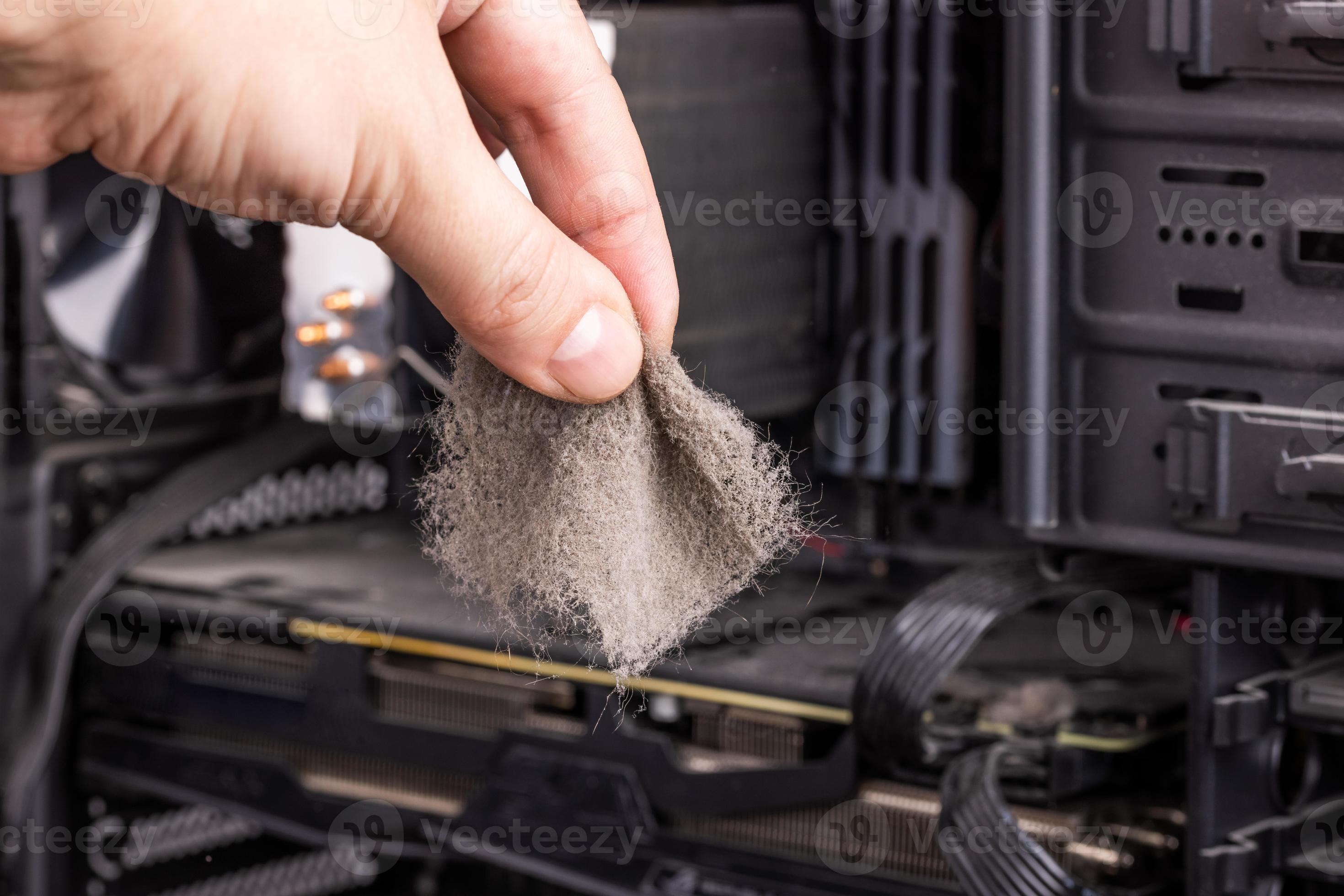 bare caucasian hand holding dust clog in front of opened pc case during