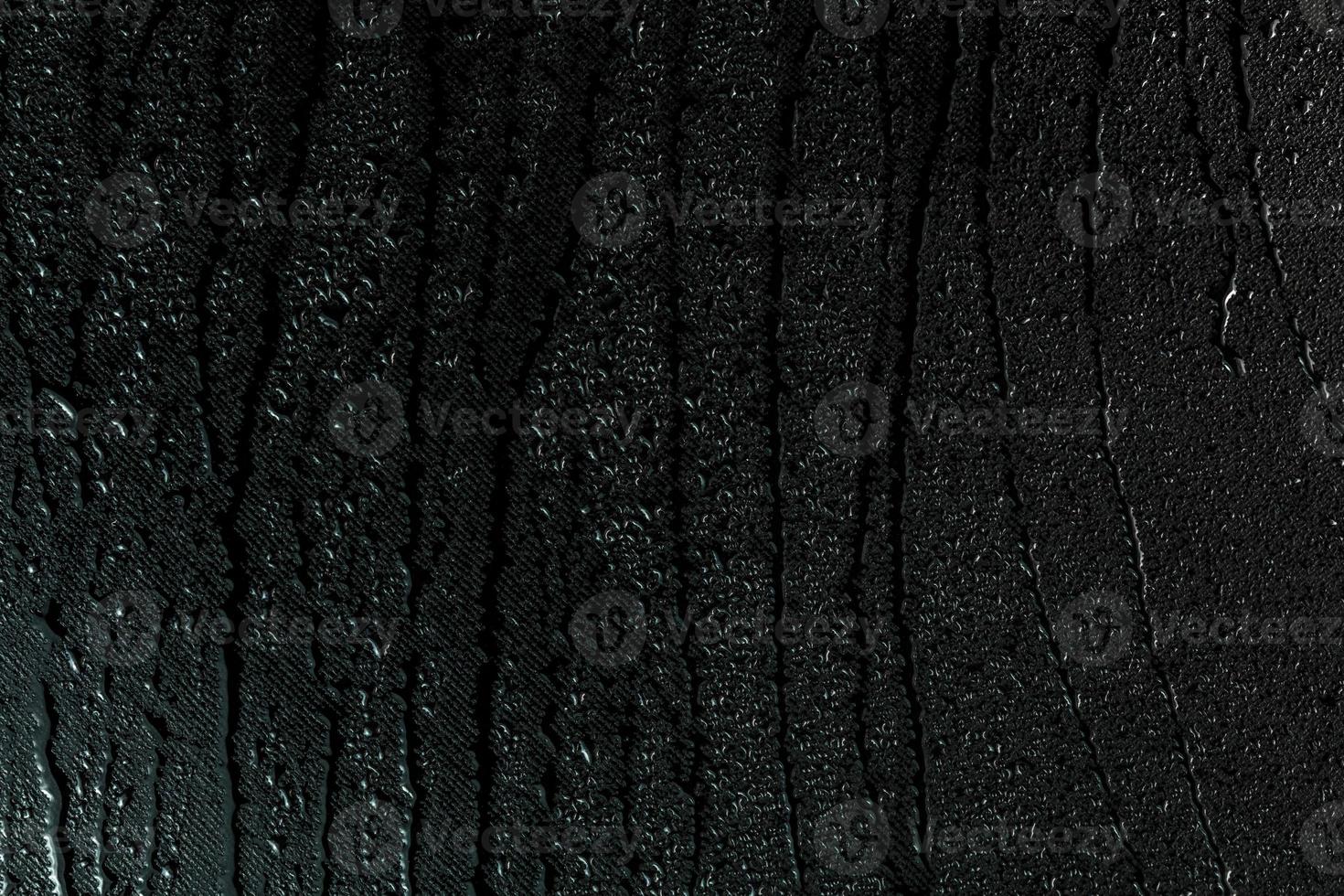 water drops on flat black rubber surface macro background with smudges photo