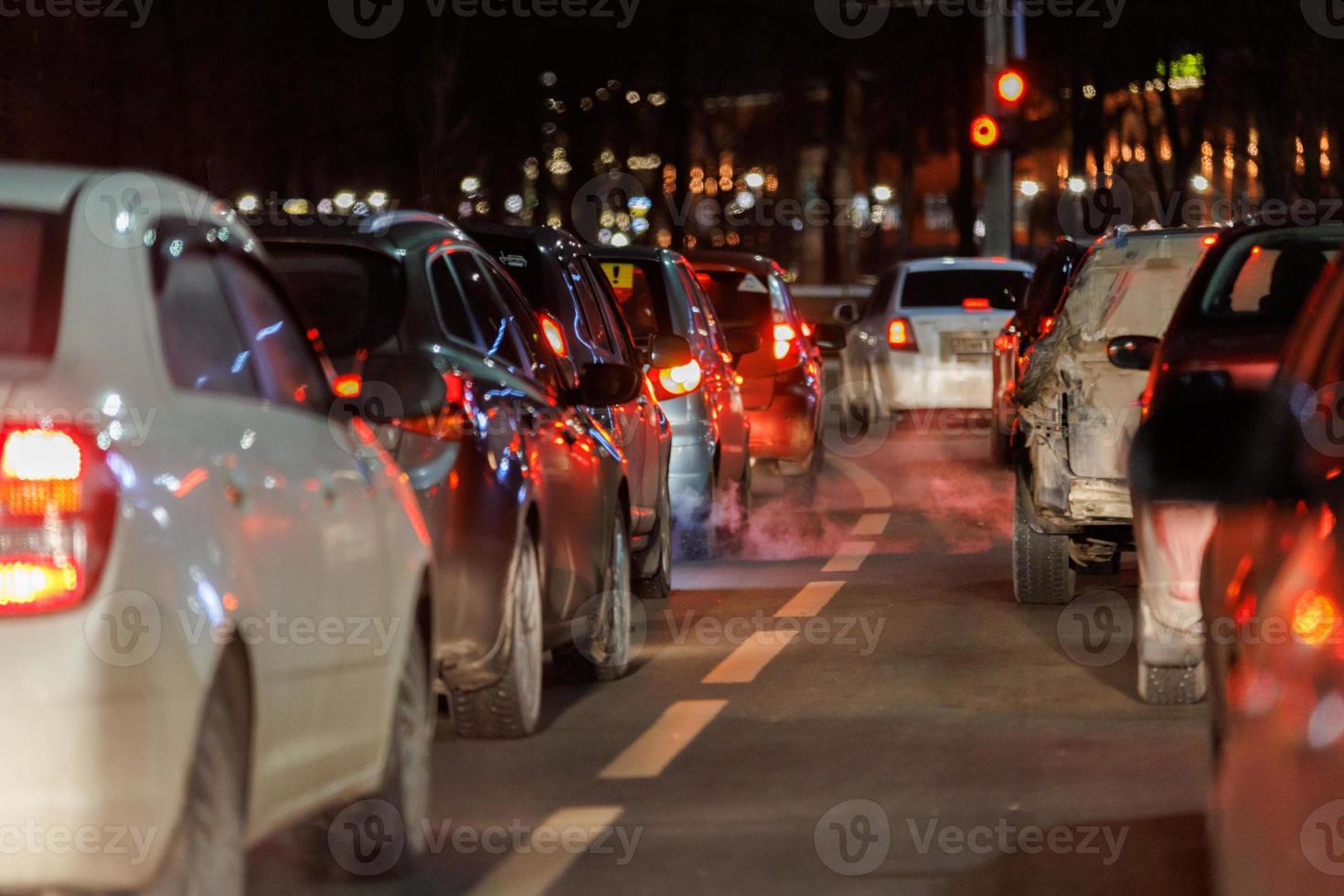 fila de autos parados frente al semáforo por la noche foto