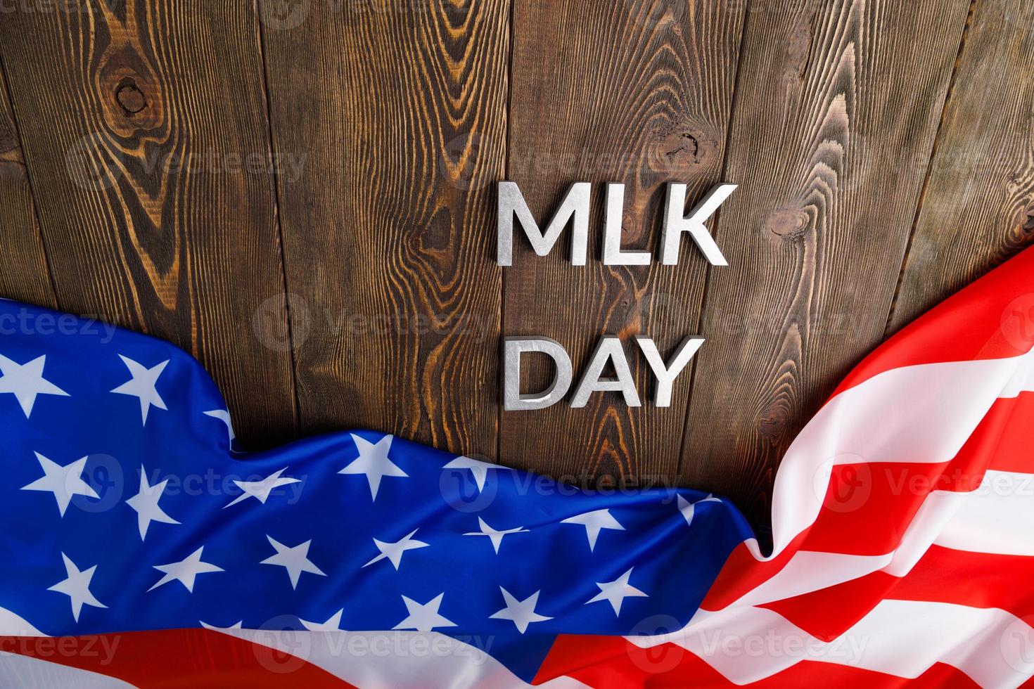 the word MLK day laid with silver metal letters on wooden surface with crumpled USA flag at upper side photo