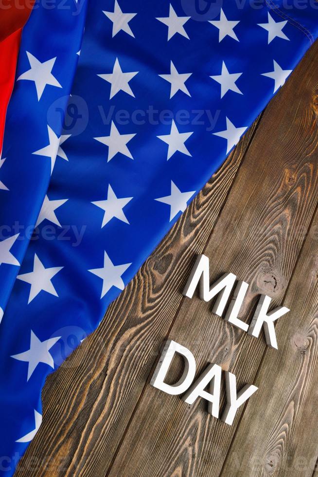 the word MLK day laid with silver metal letters on wooden surface with crumpled USA flag at left side photo