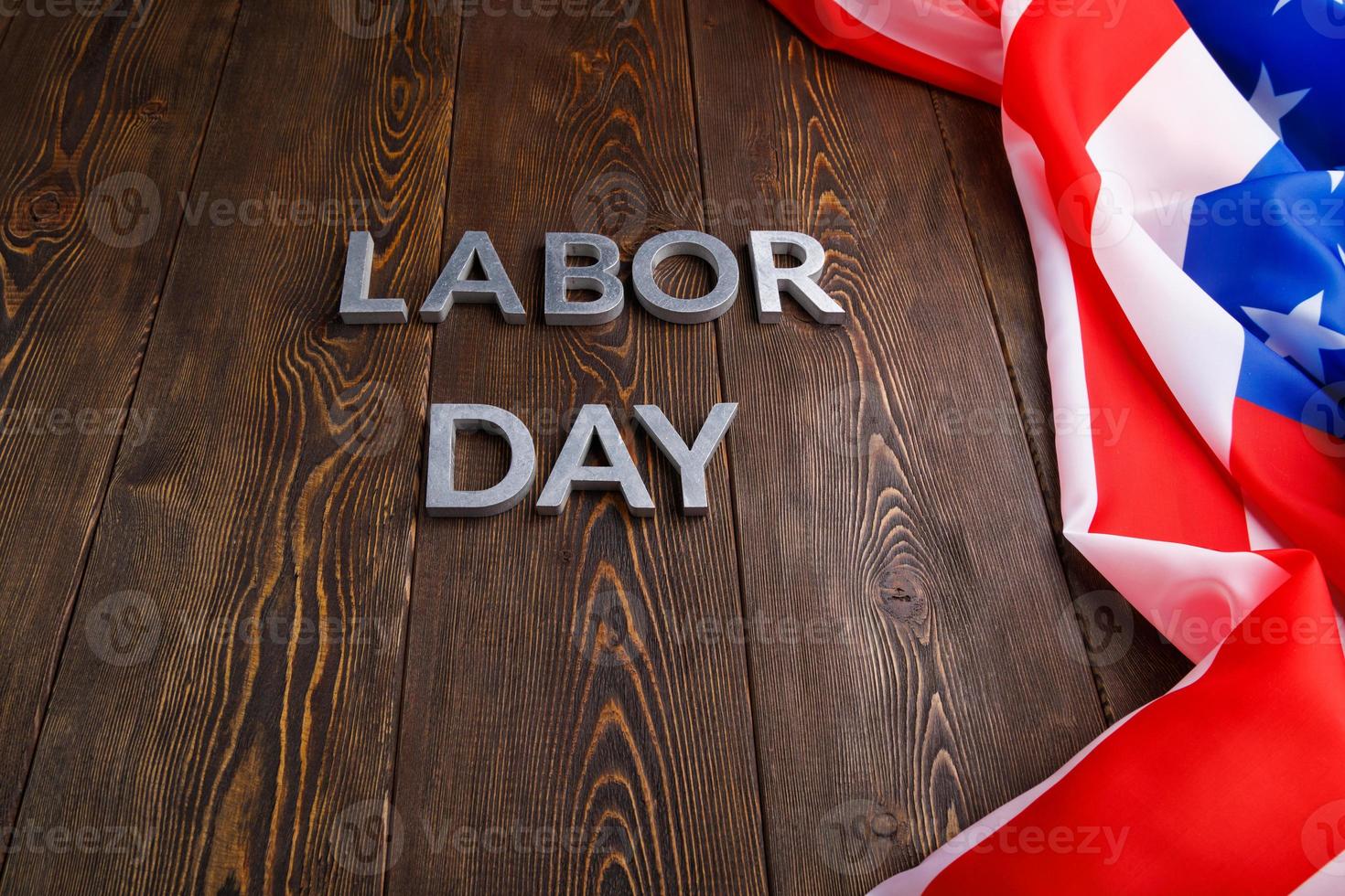 words labor day laid with silver metal letters on wooden surface with crumpled USA flag on left side photo
