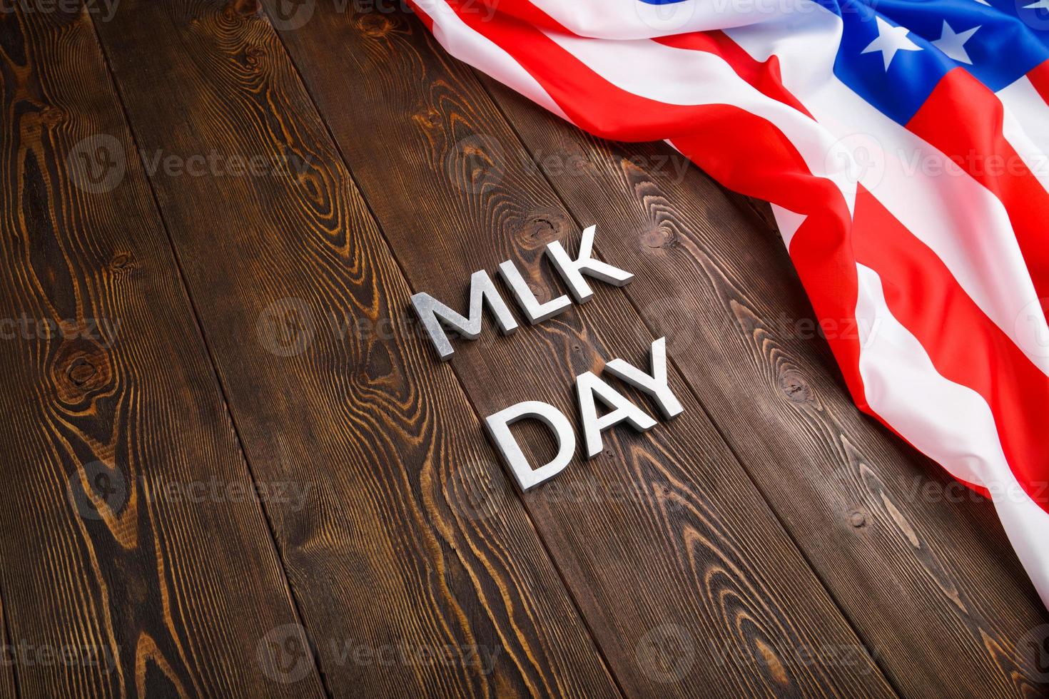 la palabra mlk day colocada con letras de metal plateado sobre una superficie de madera con una bandera de estados unidos arrugada en la parte superior foto