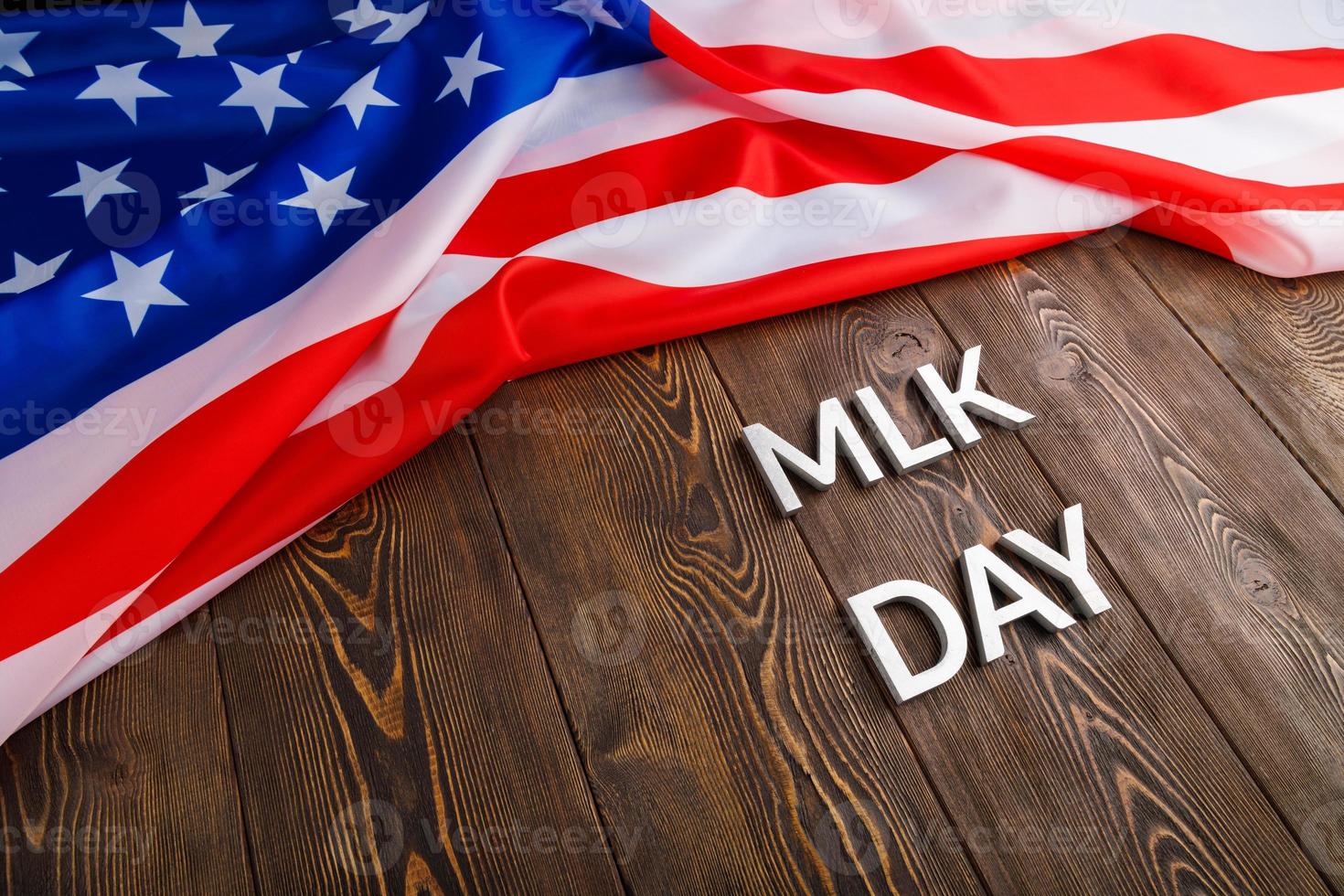the word MLK day laid with silver metal letters on wooden surface with crumpled USA flag at upper side photo