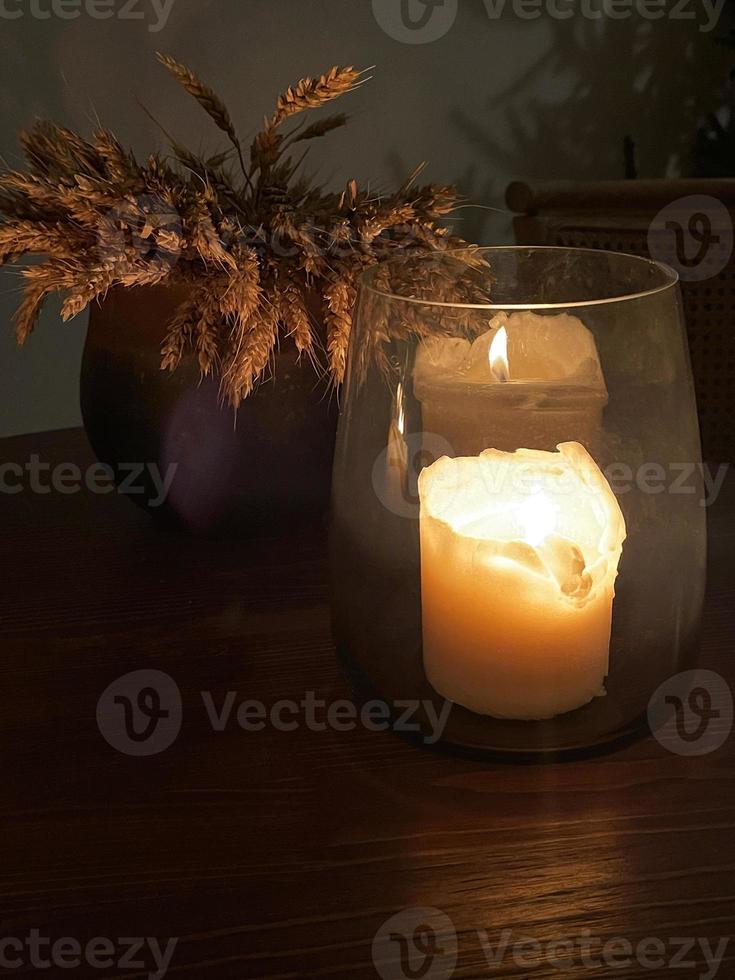 Festive table decoration, a candle in a glass candlestick burning in the dark photo