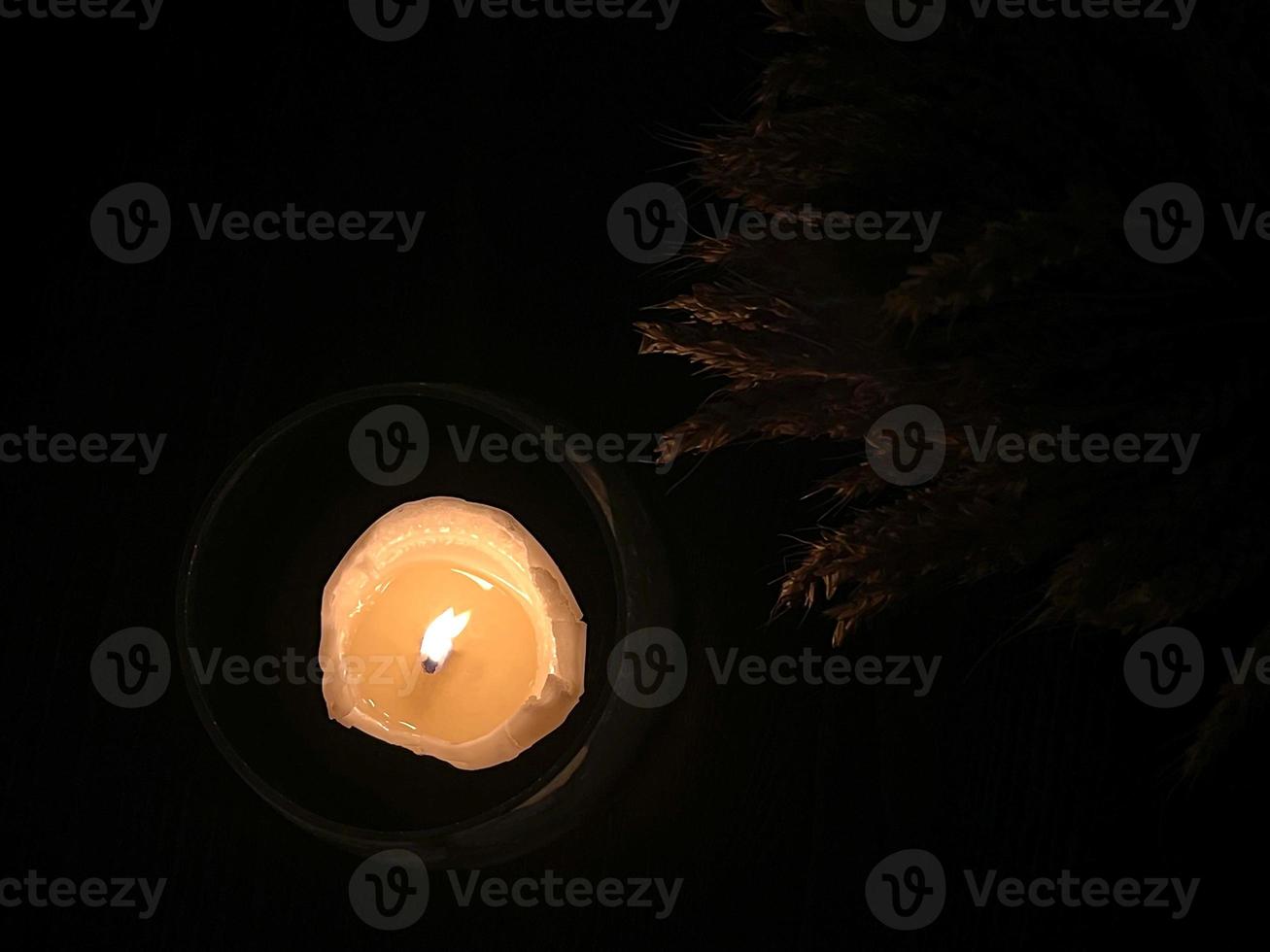Festive table decoration, a candle in a glass candlestick burning in the dark. Top view. photo