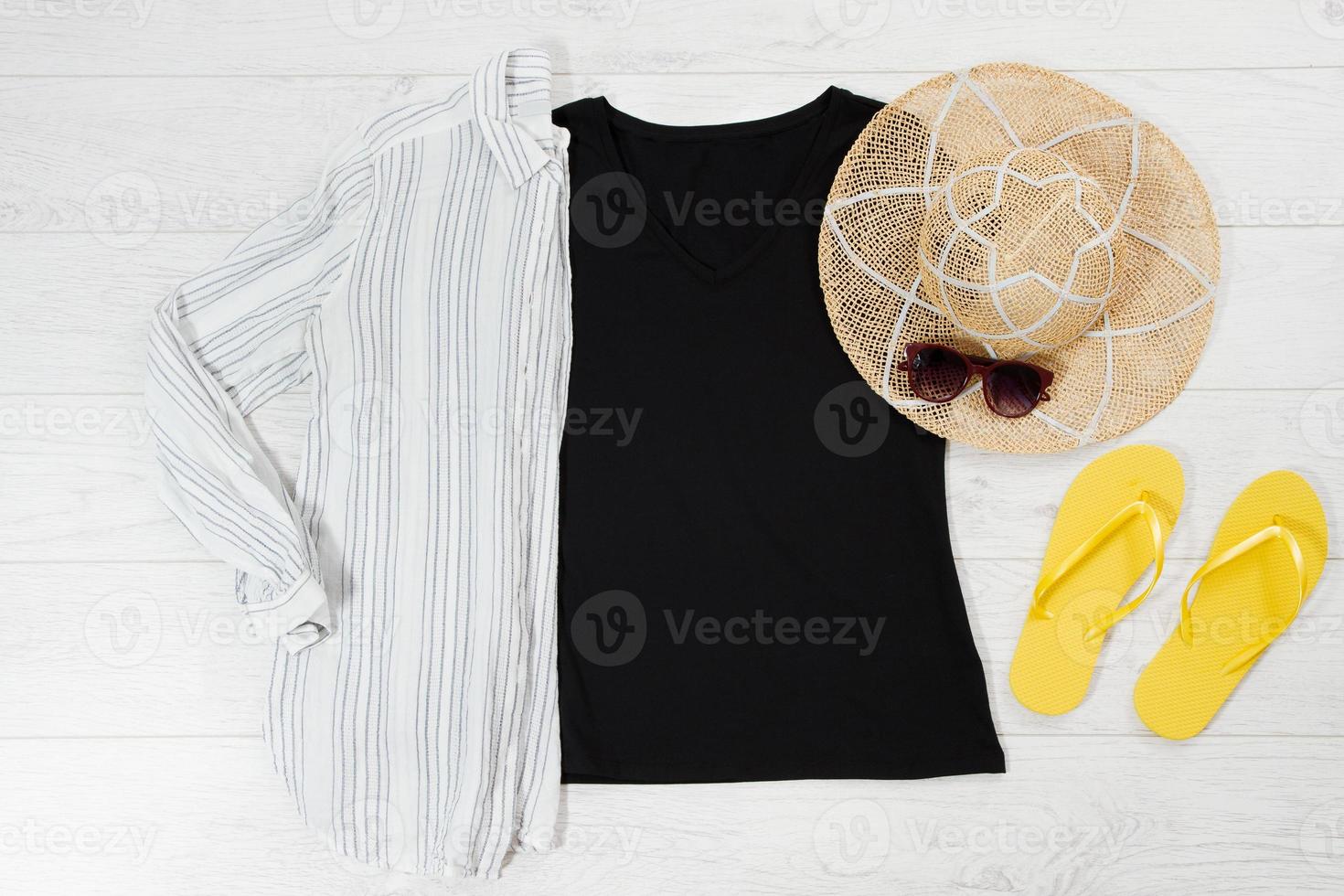 Black closeup t shirt mock up flat lay and summer flip flops on white wooden background. Top view and copy space. Mockup t-shirt and summertime. Template blank shirt. photo