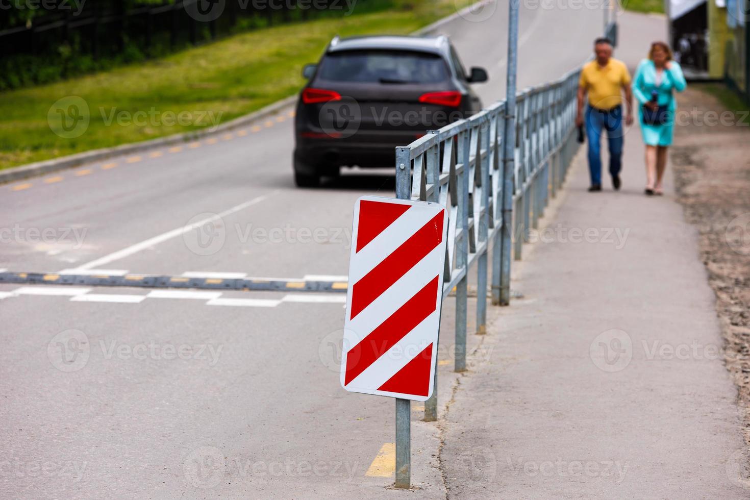 Señal de rayas diagonales rojas y blancas al final de la cerca de la carretera foto