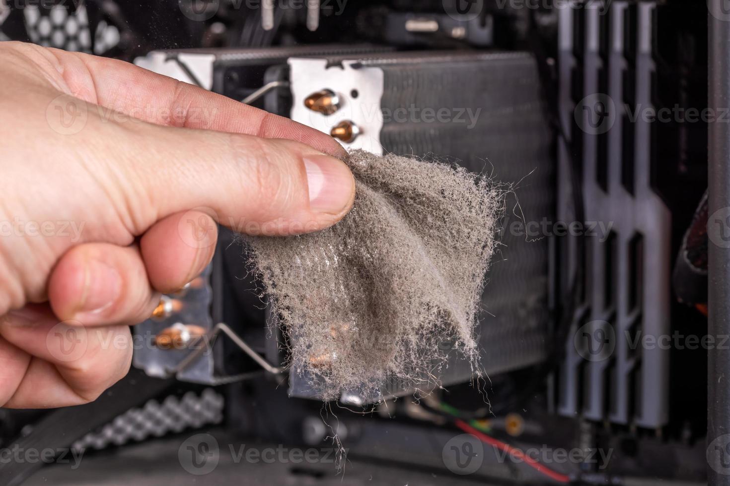 bare caucasian hand holding dust clog in front of opened pc case during maintenance photo