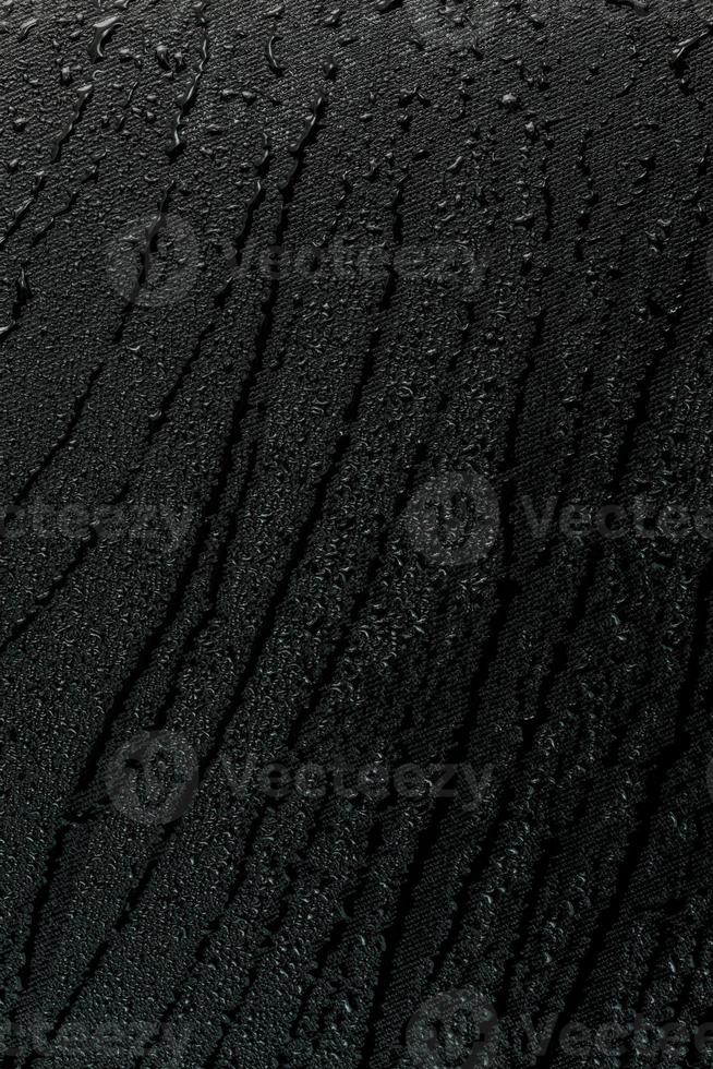 water drops on flat black rubber surface macro background with smudges photo