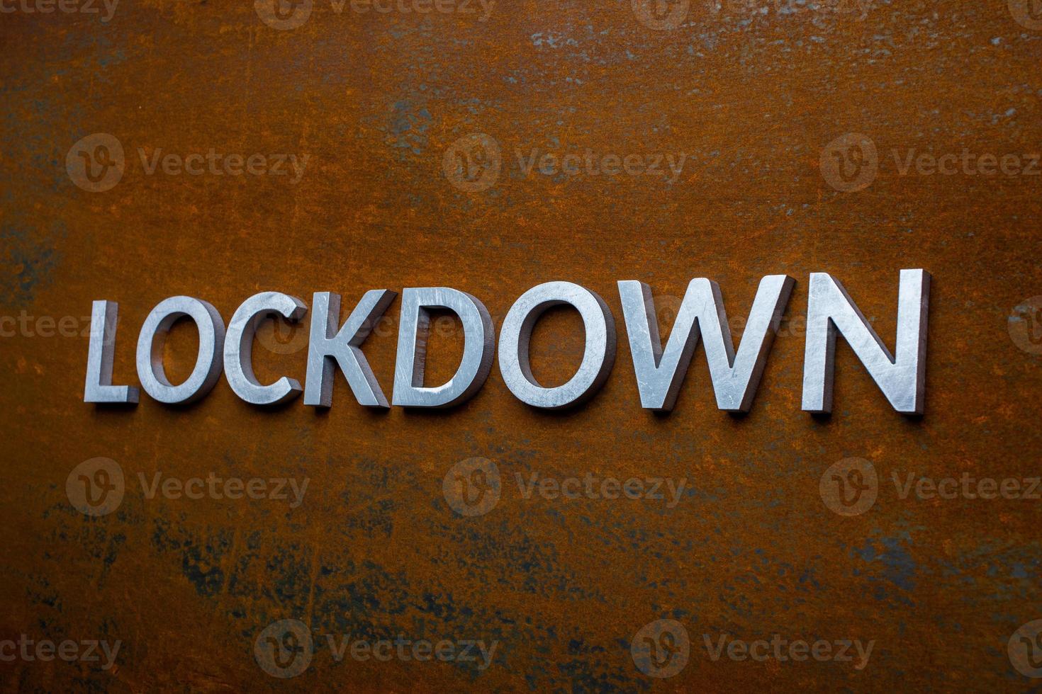 the word lockdown laid with silver metal letters on flat rusted steel sheet background in slanted linear perspective photo