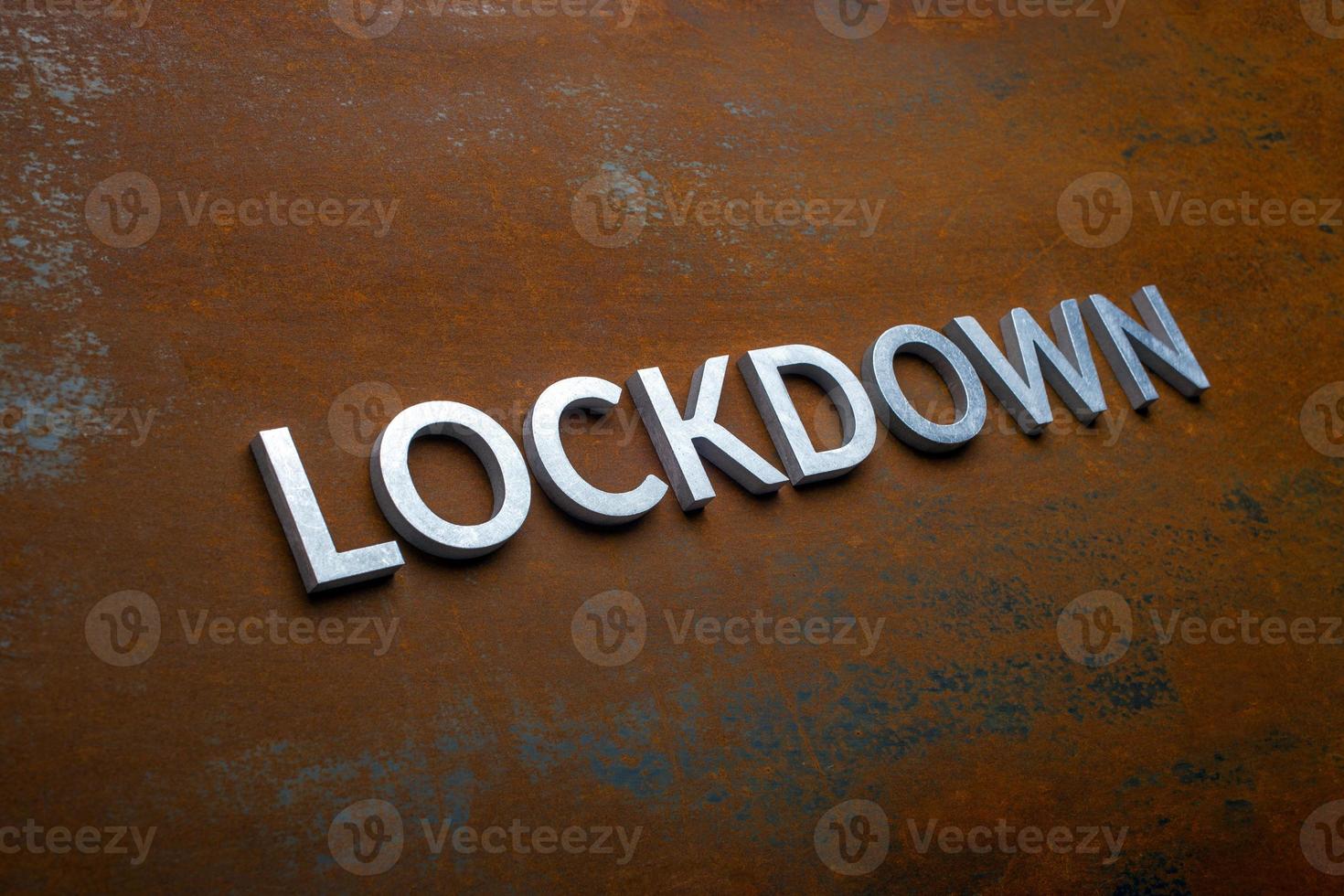 the word lockdown laid with silver metal letters on flat rusted steel sheet background in slanted diagonal perspective photo