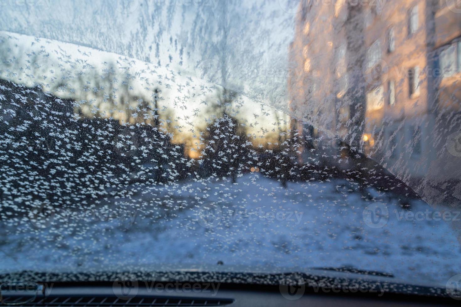 parabrisas de coche matutino con escarcha y copos de nieve, vista desde el interior foto