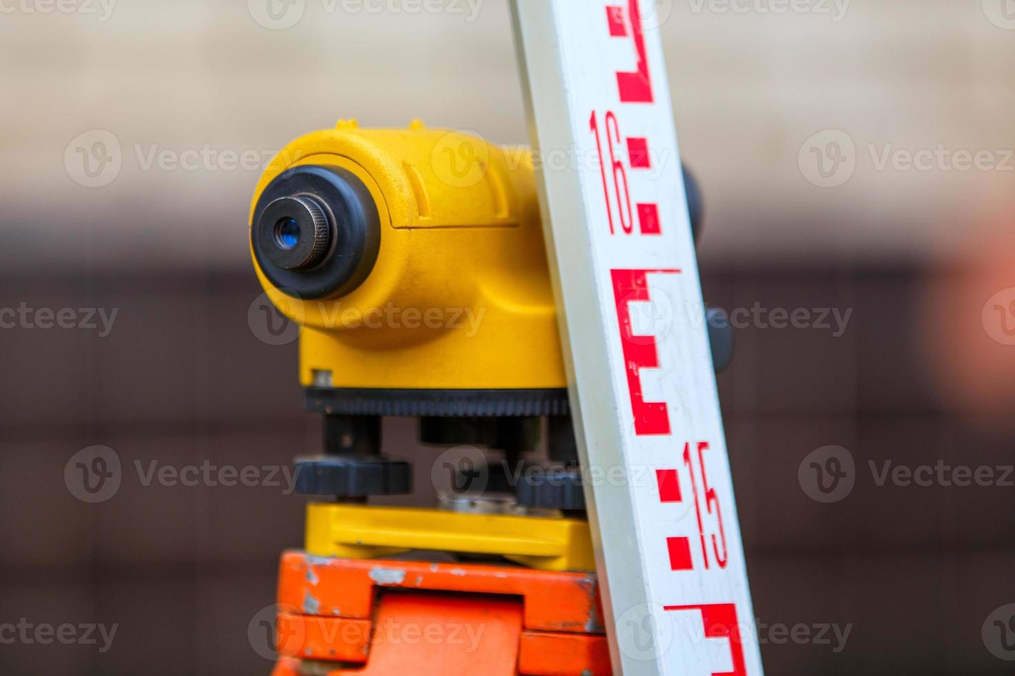 close-up view of cheap geodesy level device with tower ruler outdoors photo