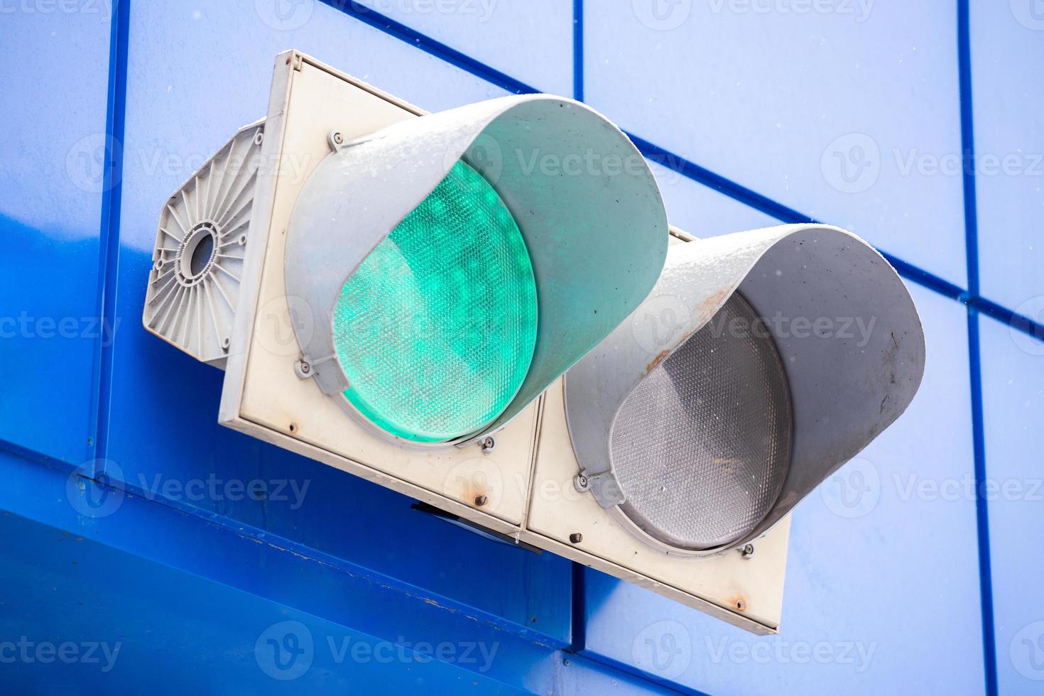 Illuminated green traffic signal light on classic blue wall of a garage photo