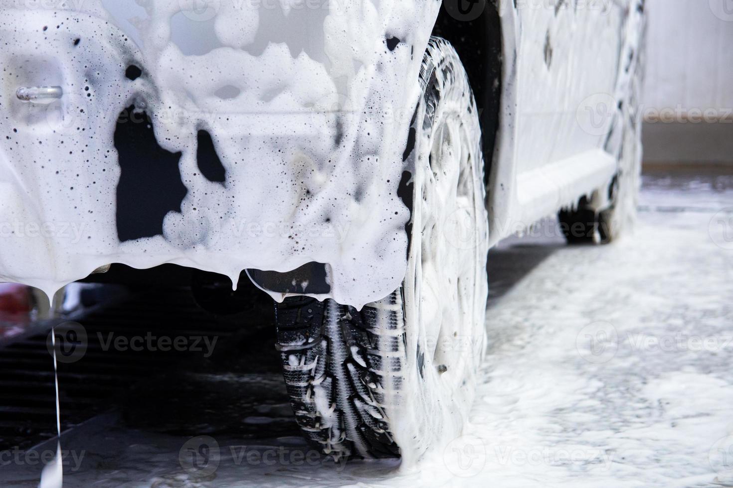 a car covered by soap foam while washing indoors - close-up low position view from back with selective focus photo