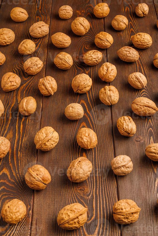 many walnuts with shells evenly spread out on brown wooden surface photo