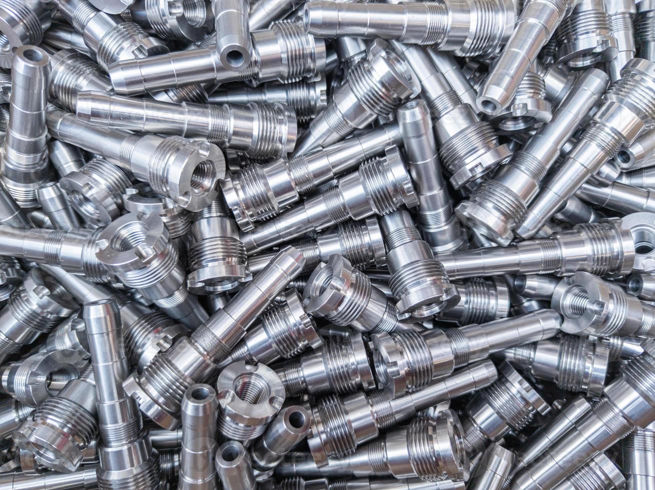 Full frame background of pile of shiny long steel parts, clean steel rods after fine cnc turning - laying chaotically with selective focus. photo