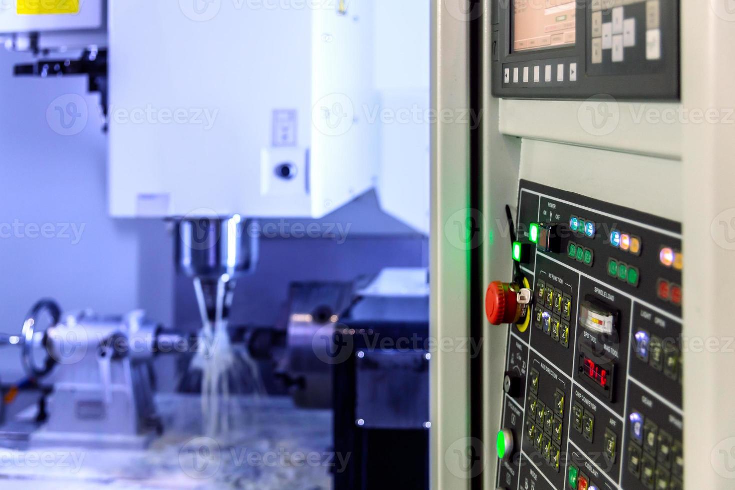 A modern 4-axis cnc vertical milling machine working with water cooling, selective focus on foreground photo