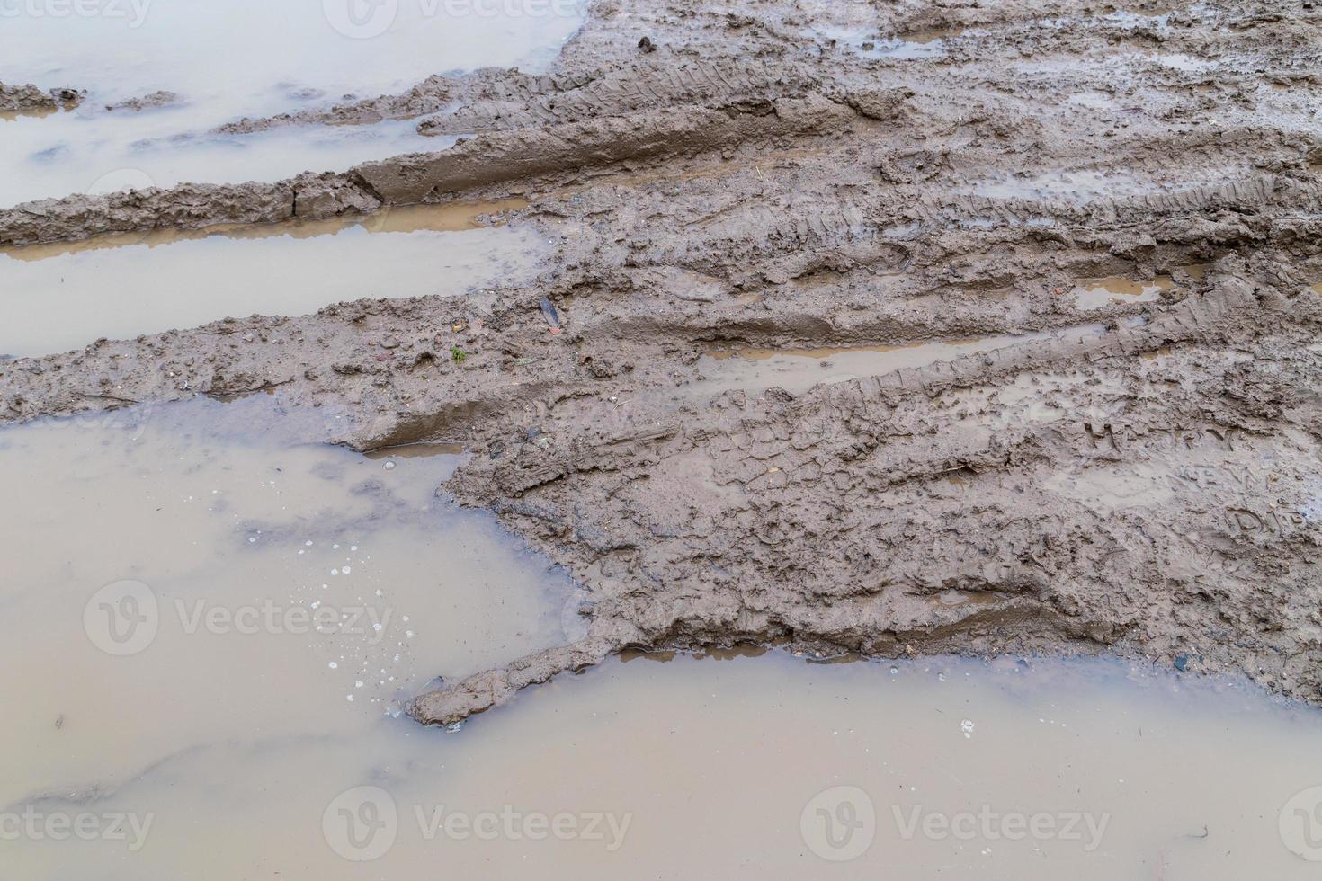 dirty clay mud road with tire tracks at day time - full frame background with hard sun light photo