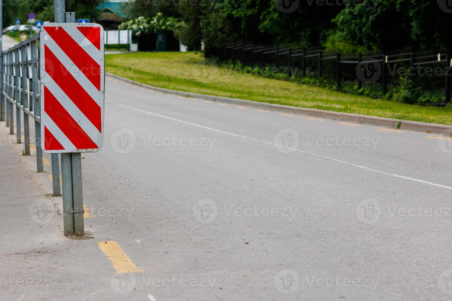 red and white diagonal striped sign at road fence end photo