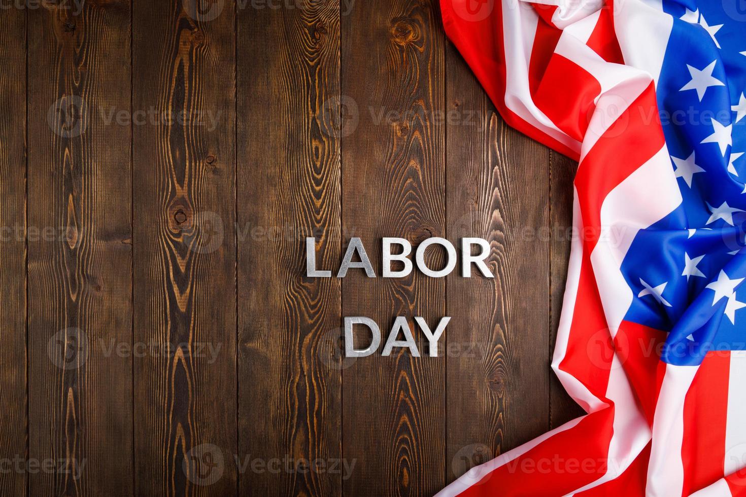 words labor day laid with silver metal letters on wooden surface with crumpled USA flag on right side photo