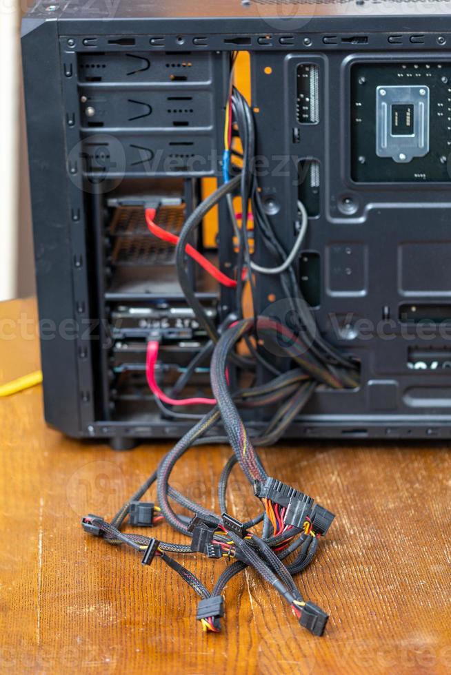 bunch of computer wires sticking out from opened black pc case - close-up with selective focus photo