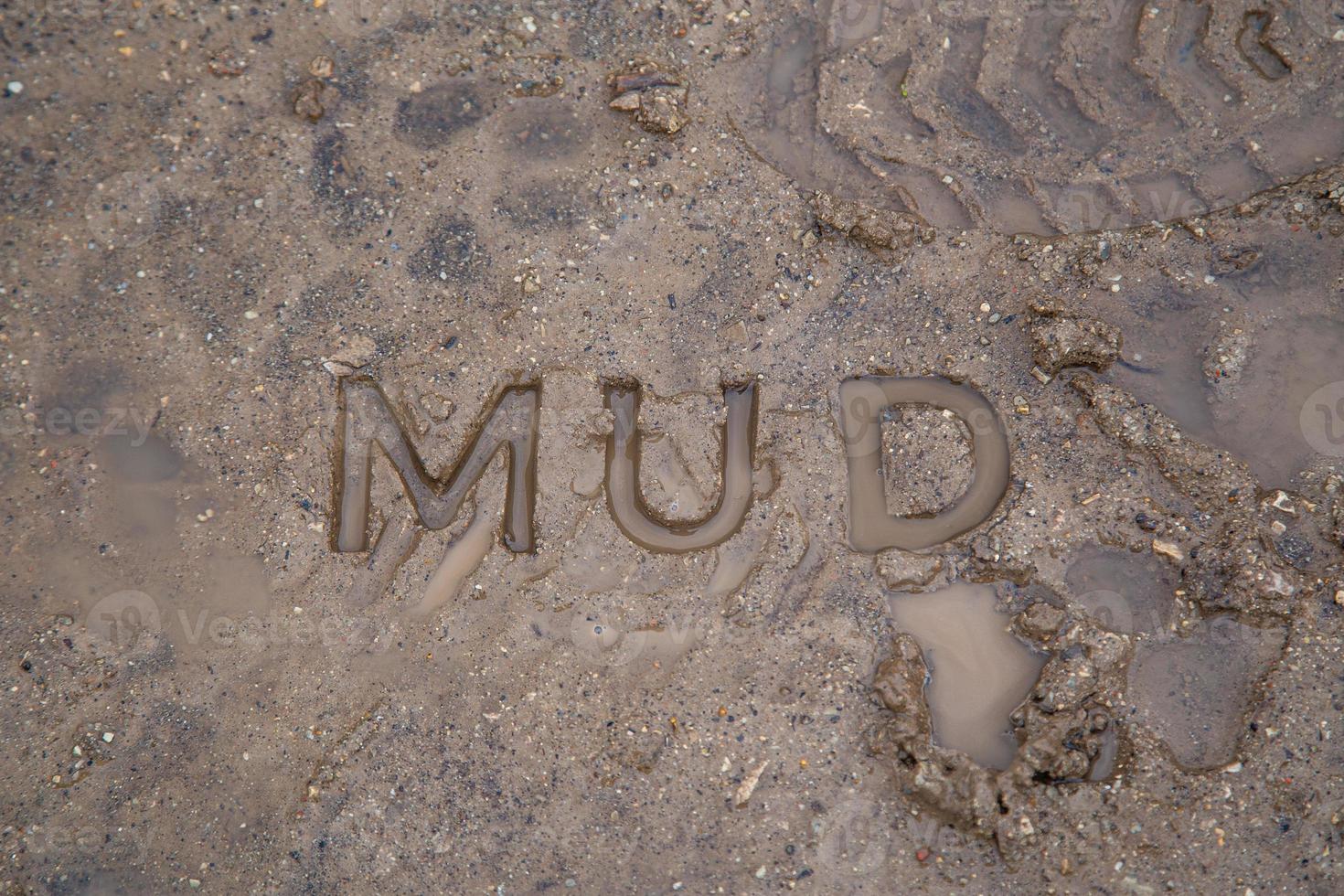 the word mud imprinted in wet dirt road surface - close-up with selective focus photo
