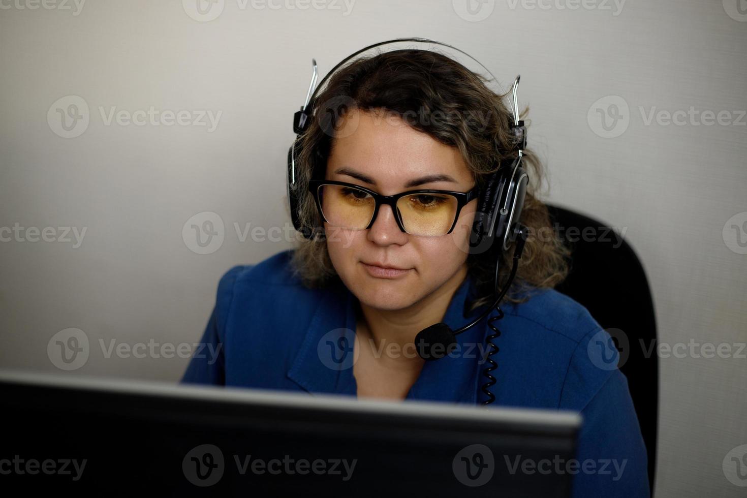A serious call center operator is talking to a client while looking at a computer screen in close-up. photo