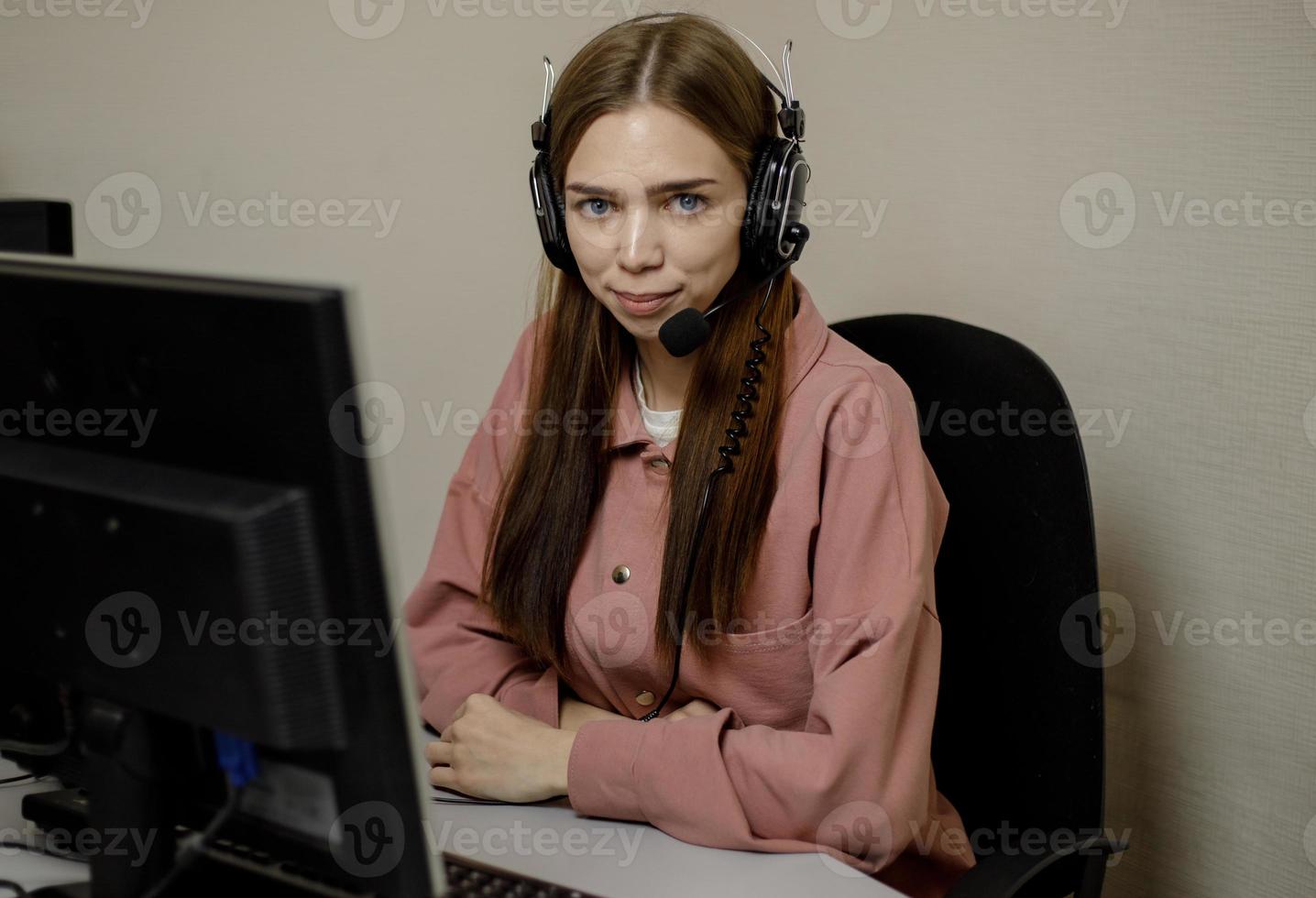 A happy call center agent working on a support hotline in the office. Close-up. A telemarketer, a telemarketing agent, makes a conference video call, talks to an online client on a computer. photo