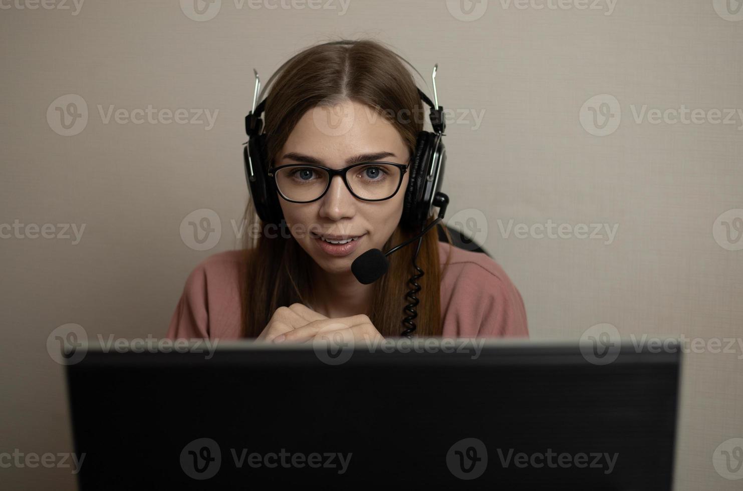 A happy call center agent working on a support hotline in the office. A call center operator is talking to a customer while looking at a computer screen in close-up photo