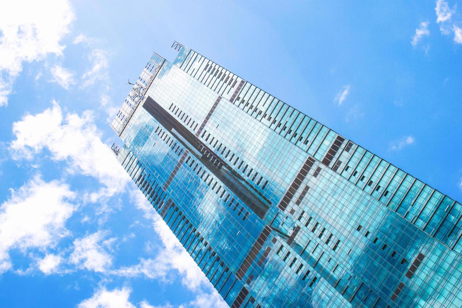 kuala lumpur, malasia, 21 de febrero de 2020. vista inferior del rascacielos sobre un fondo de cielo azul con reflejo de nubes en las ventanas. foto