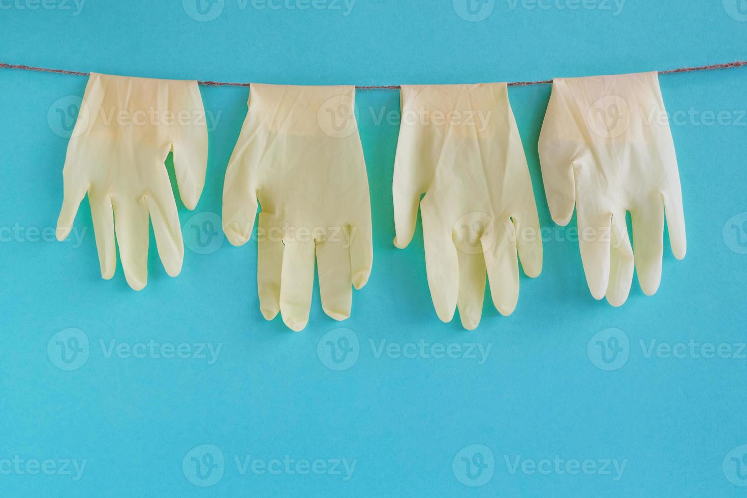Drying of disposable medical gloves after washing on a rope for reuse, on a turquoise background. Concept of new normal lifestyle. photo