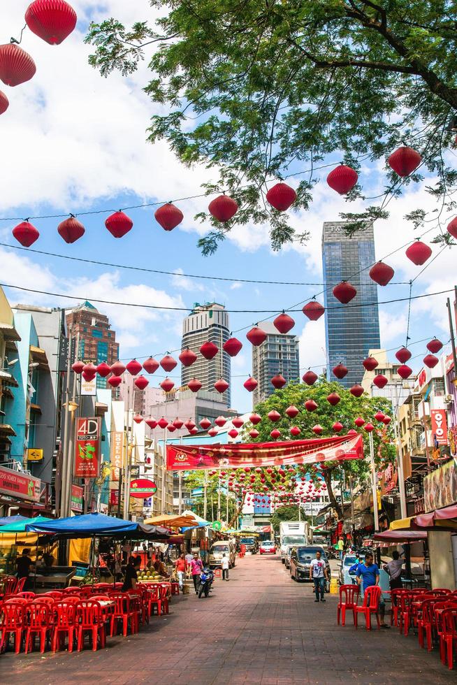 Kuala Lumpur, Malaysia, February 22, 2020. View on busy street with cafes, local shops and Chinese red lanterns on a background of downtown with skyscrapers. photo