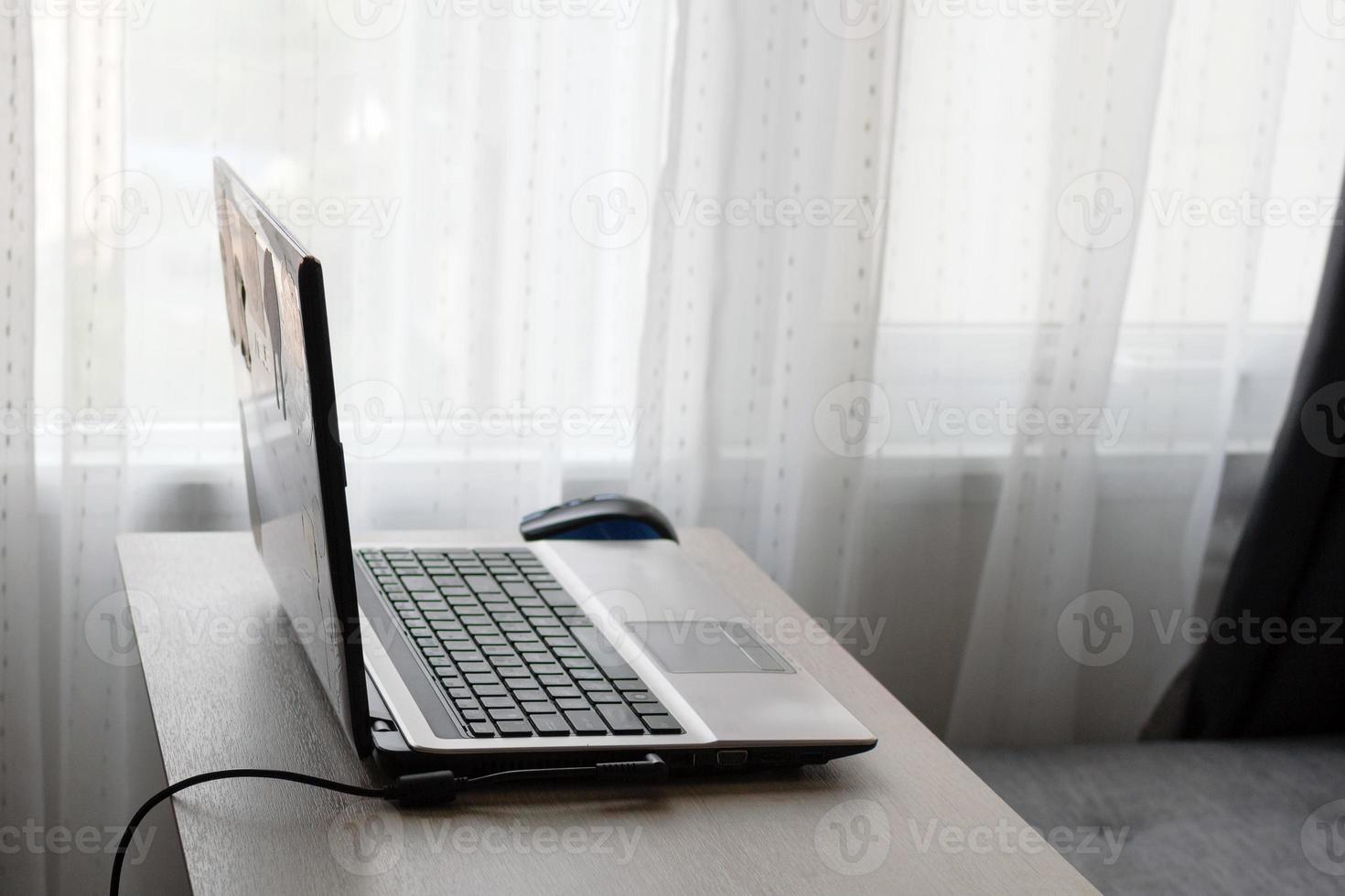 Home office concept. Work from home on the table with laptop and gray sofa near to window. photo