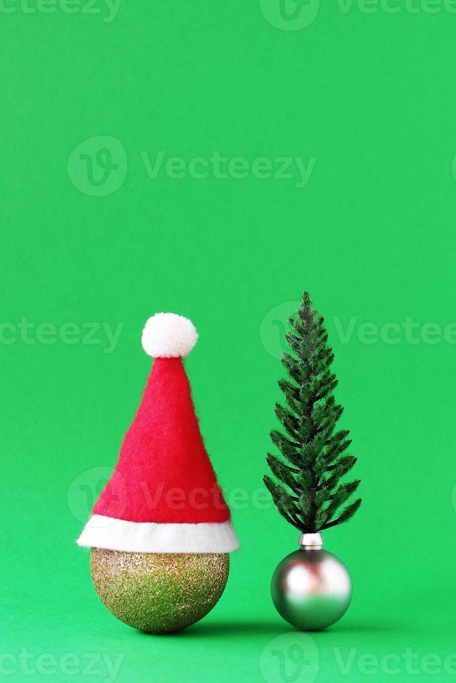 Christmas decorations - shiny gold and silver balls with Christmas tree and Santa Claus red hat tree on green background with copy space. photo